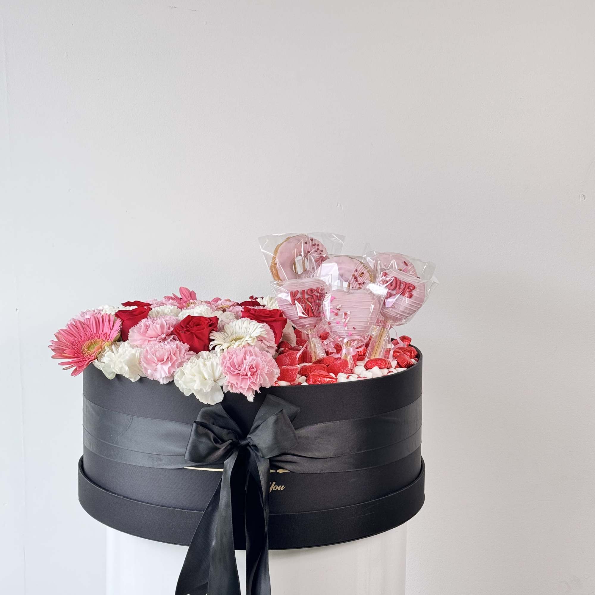 Black gift box with pink and white flowers and heart-shaped lollipops
