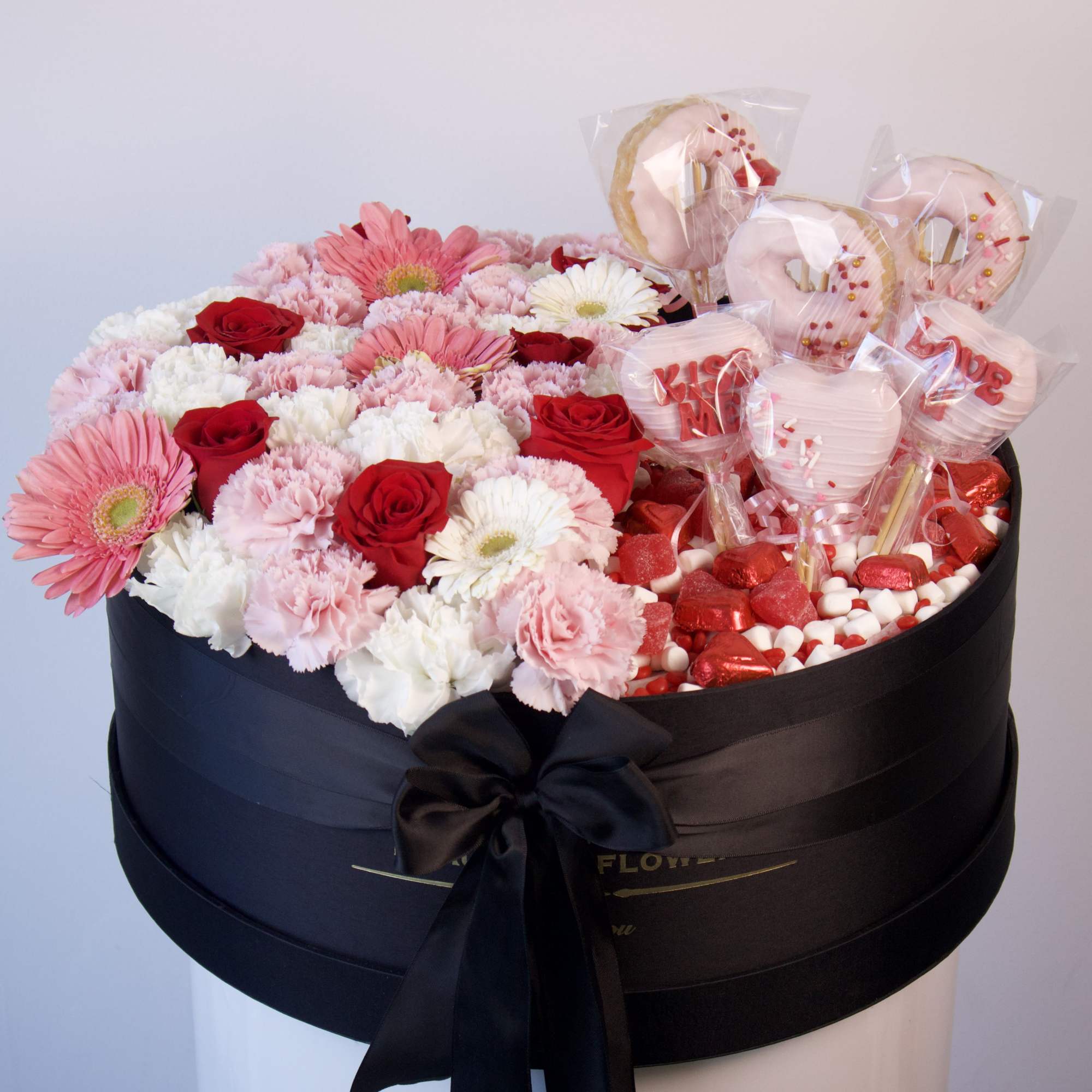 Pink and red flower box with roses, gerbera daisies, and candy hearts