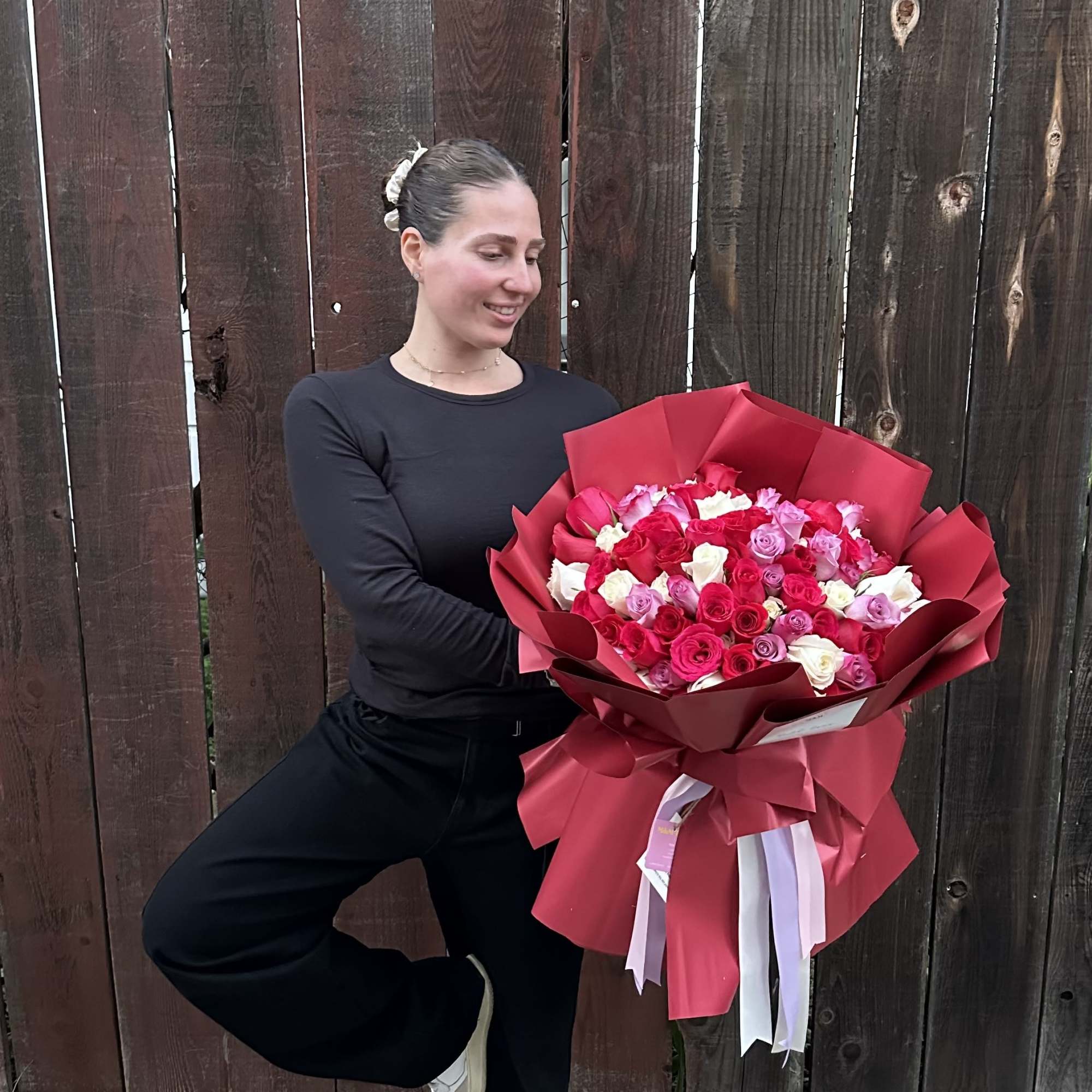 Large bouquet of pink, red, and white roses wrapped in red paper