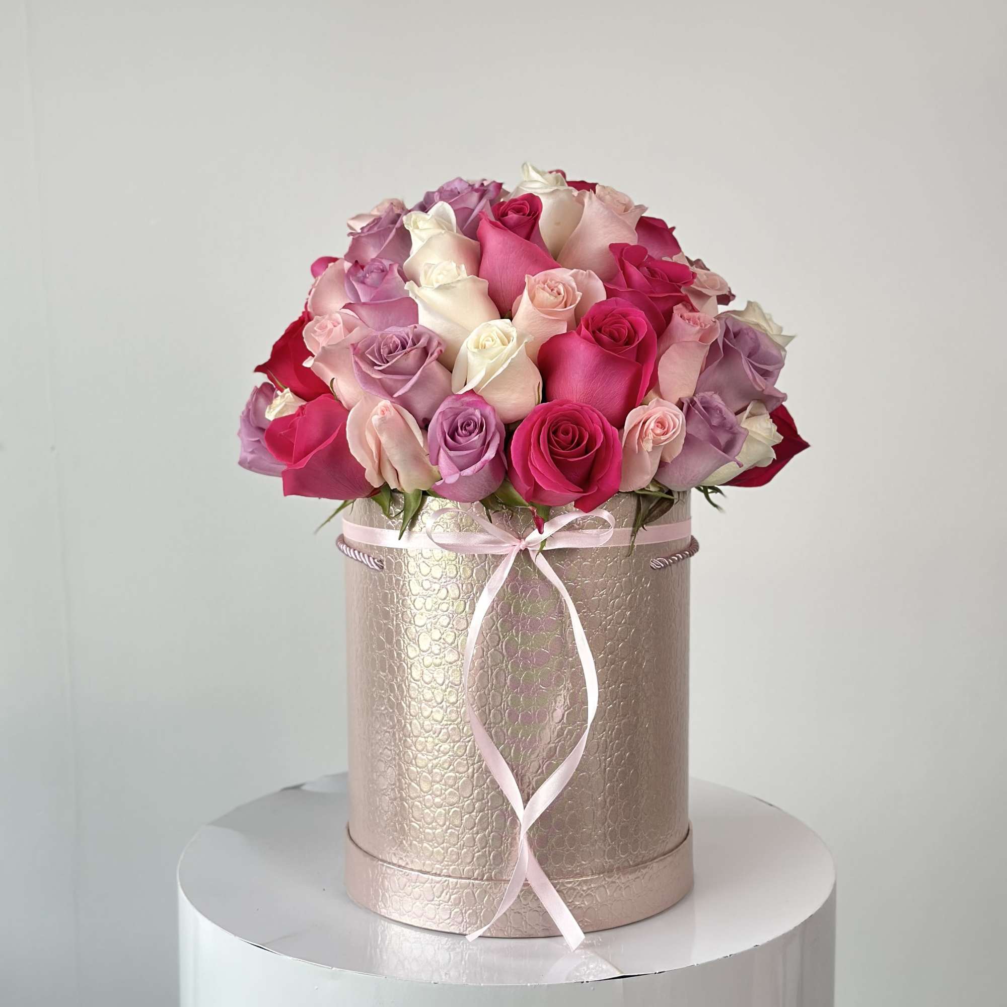 Bouquet of pink, white, and lavender roses in a round gift box