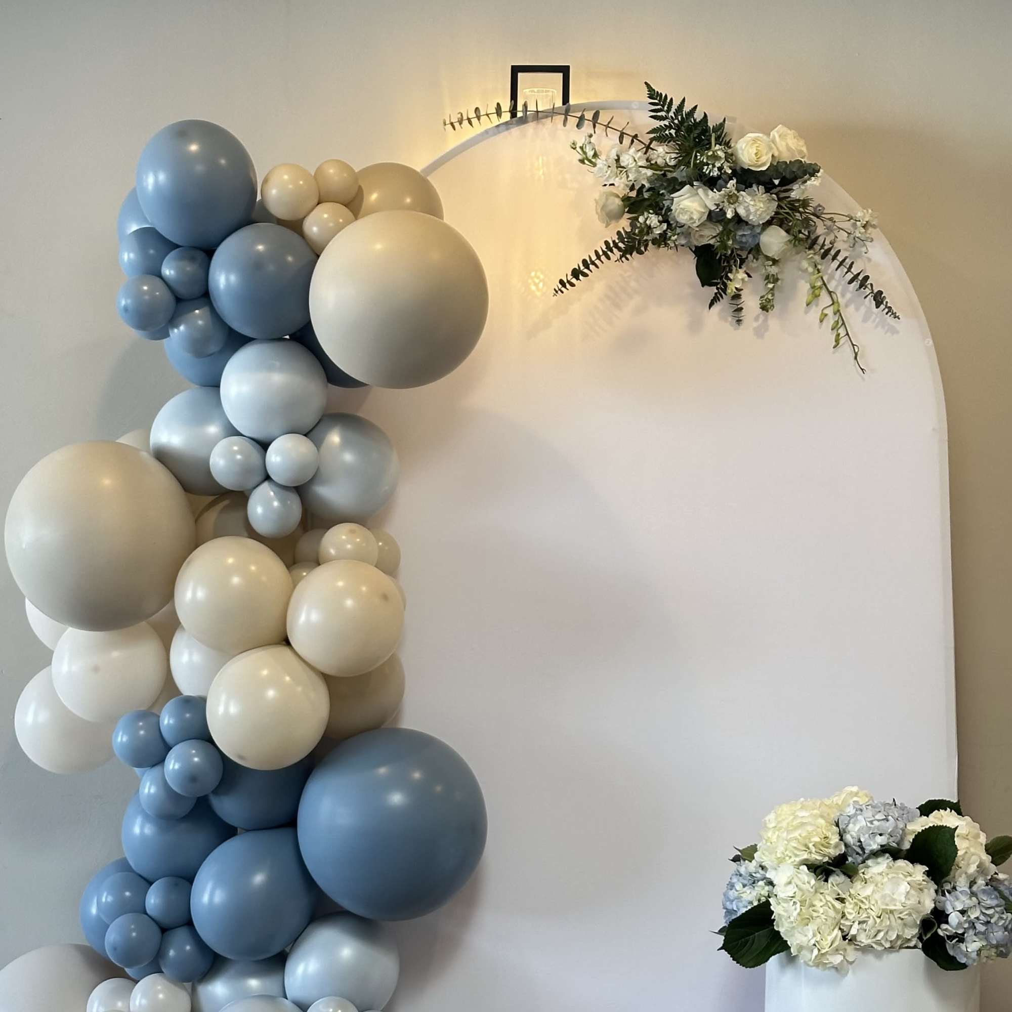 Blue and cream balloon arch with white floral accents