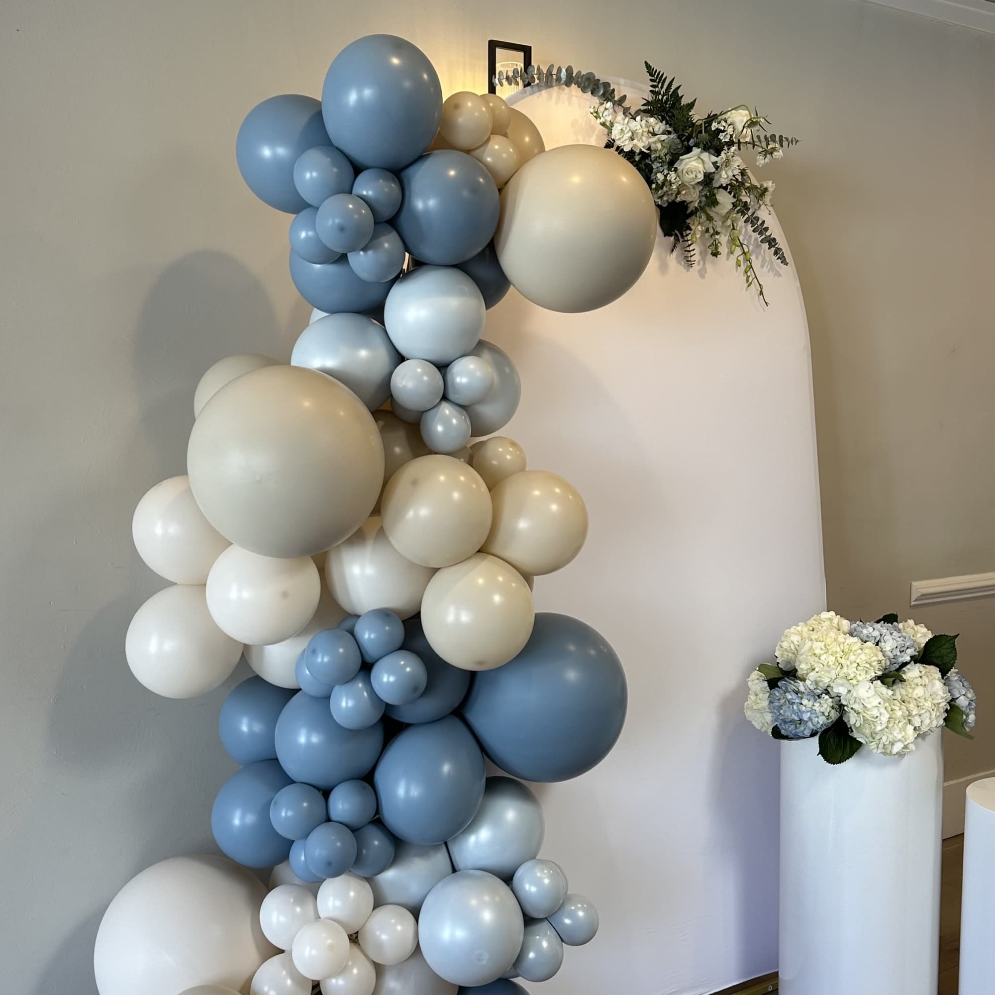 Blue and white balloon arch with small white floral accents
