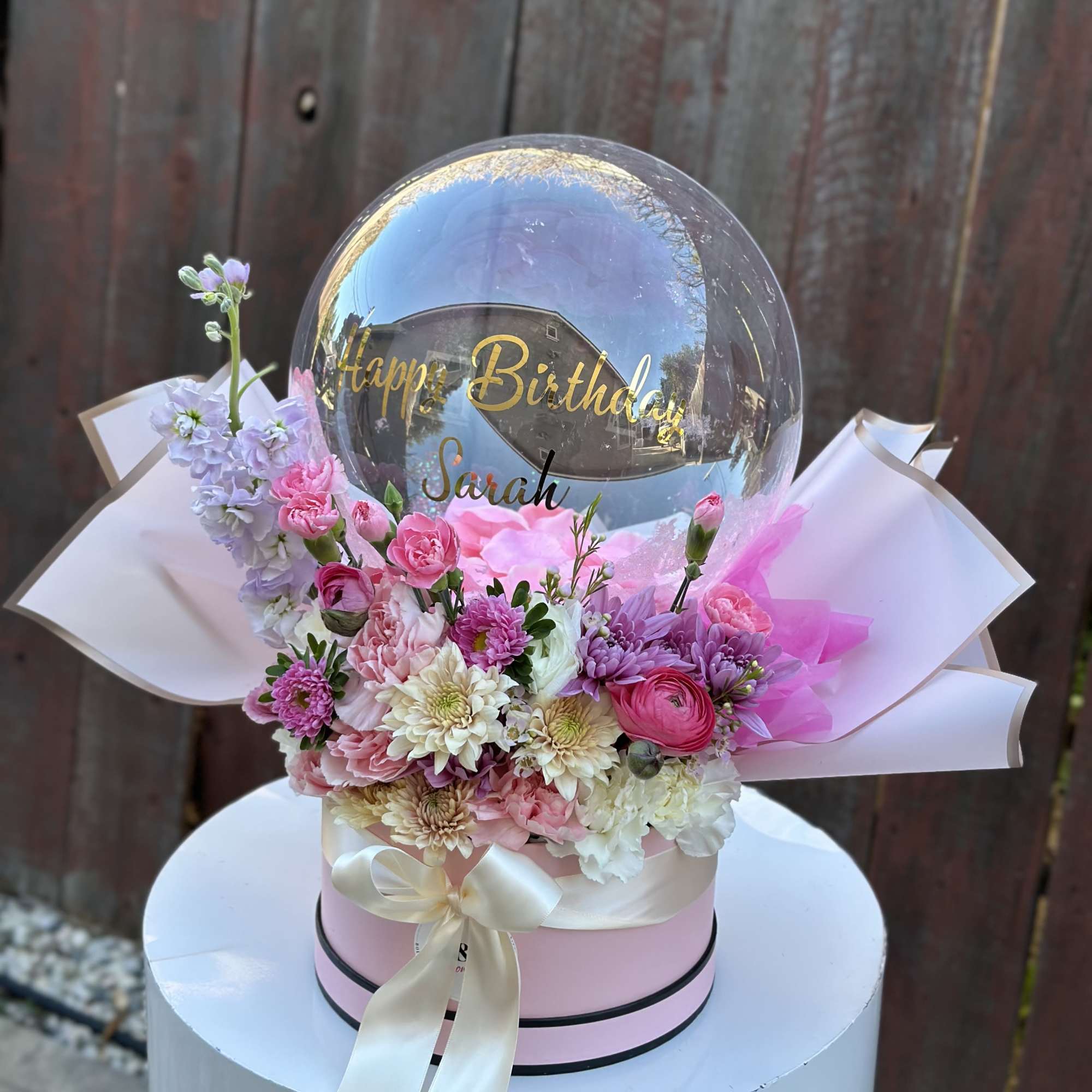 Pink and white flower arrangement with a clear birthday balloon