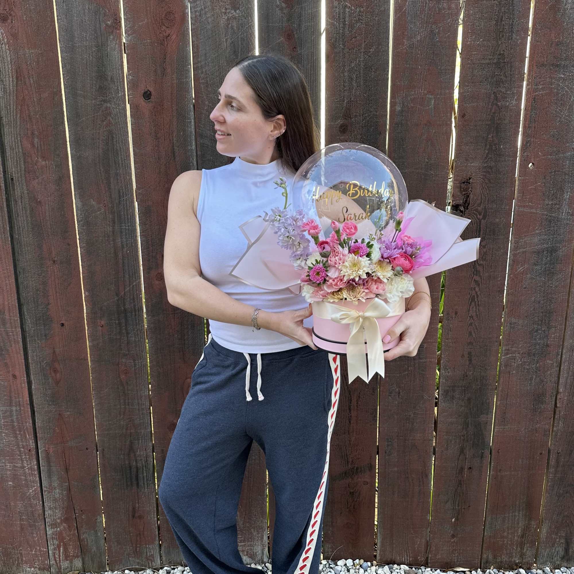Woman holding a pink flower box with a clear birthday balloon