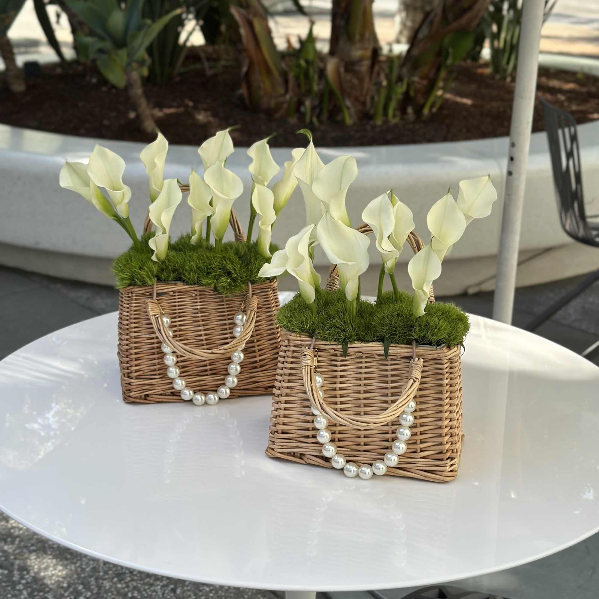 Two wicker baskets with white calla lilies and pearl garlands on a table