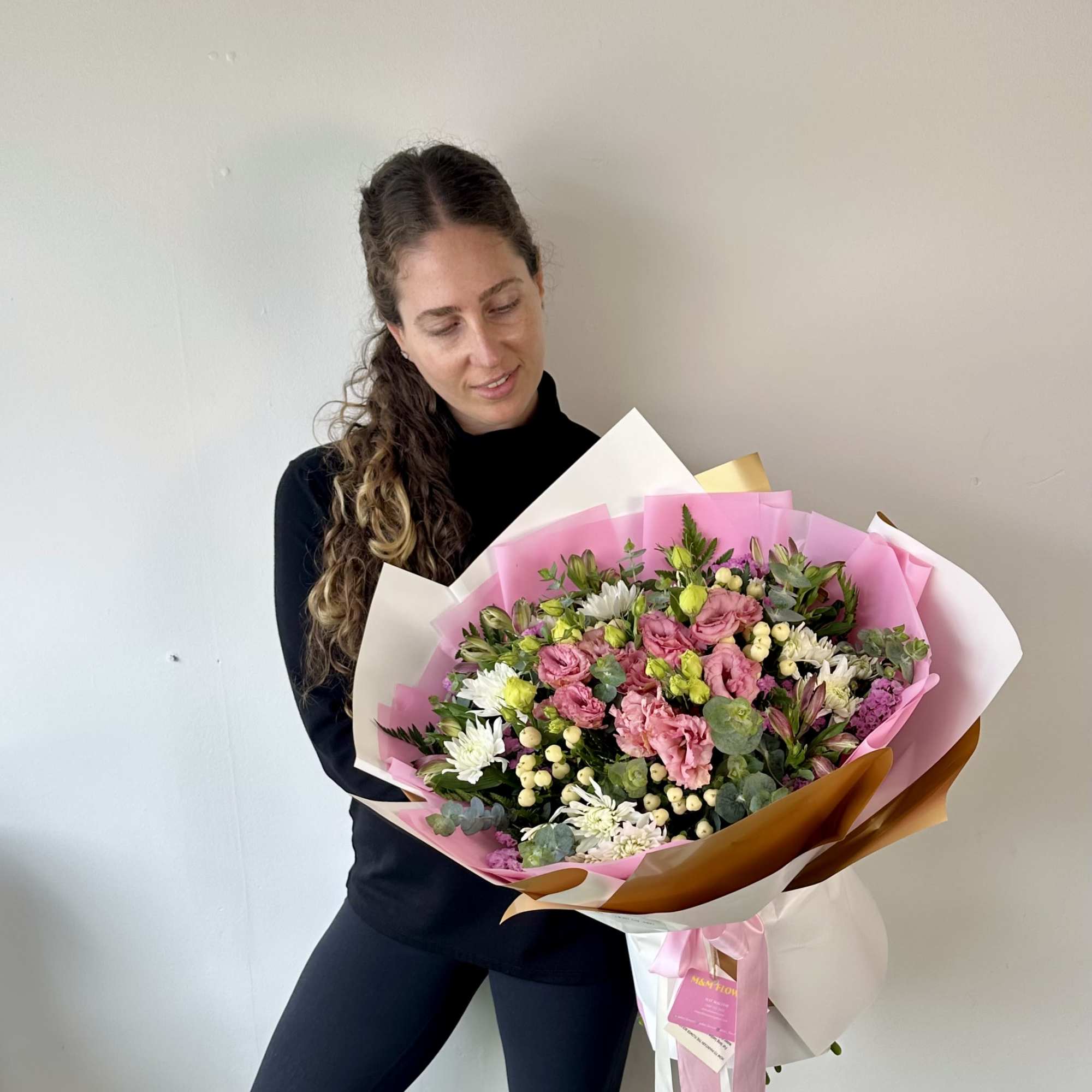 Woman holding a large bouquet of pink and white flowers wrapped in pink paper