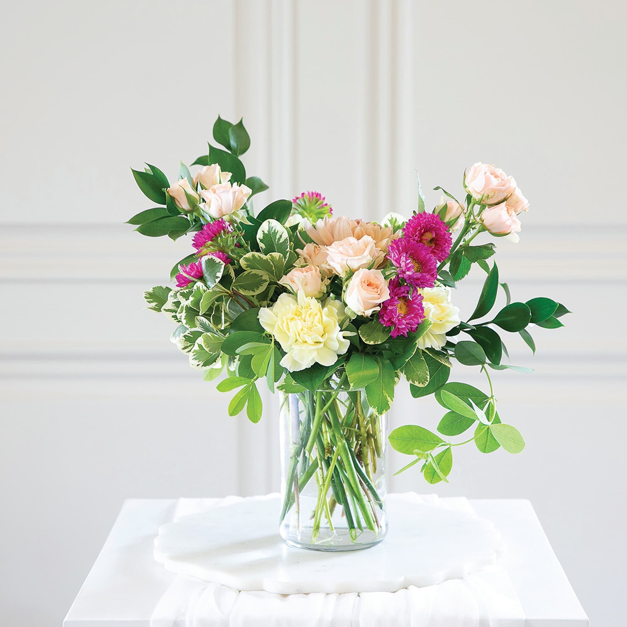 Mixed bouquet of pastel roses and chrysanthemums in a clear glass vase