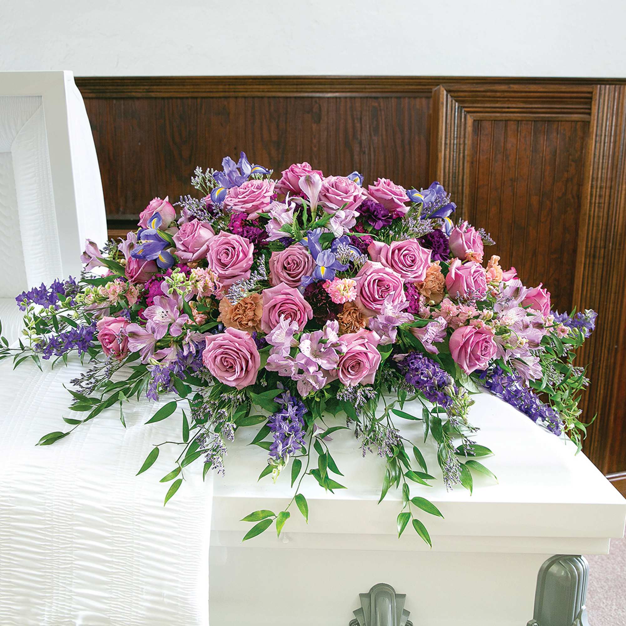 Pink and purple floral arrangement on a white casket