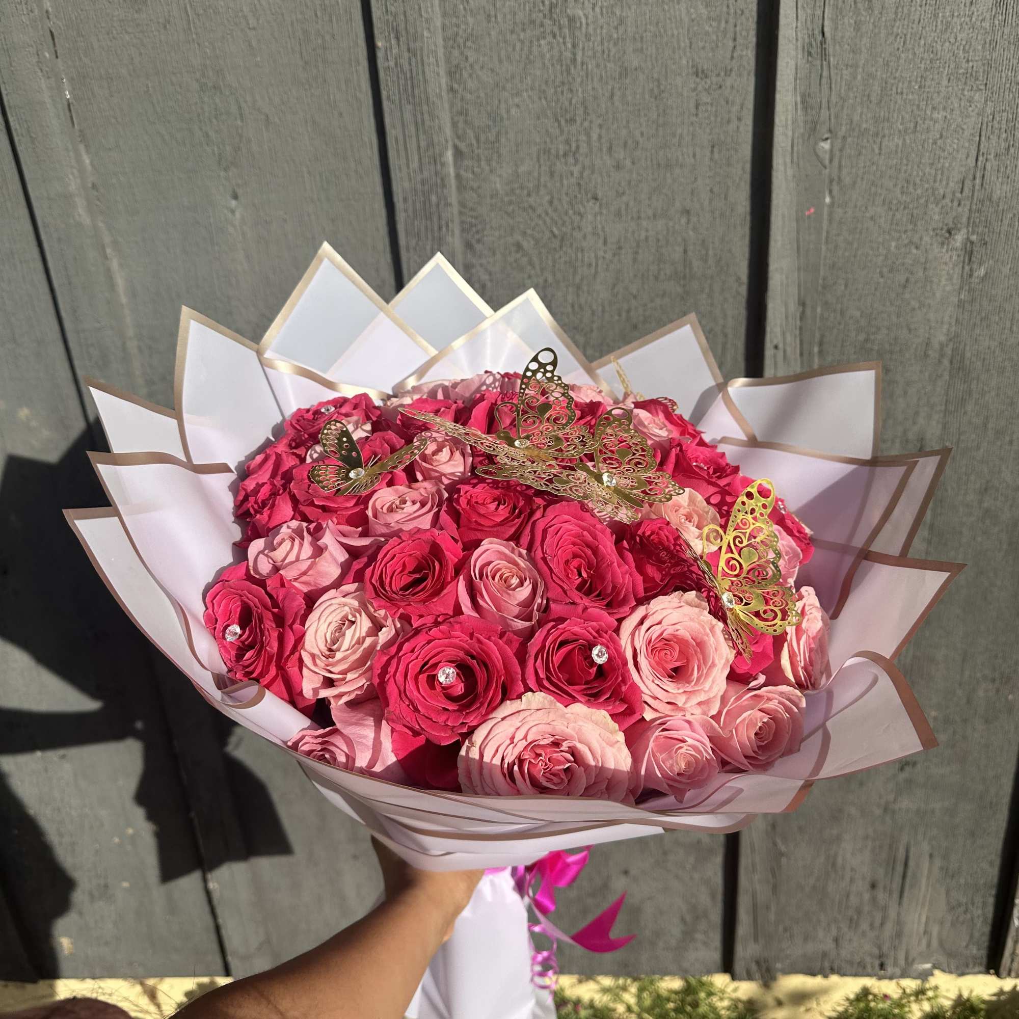 Bouquet of pink and hot pink roses wrapped in white paper