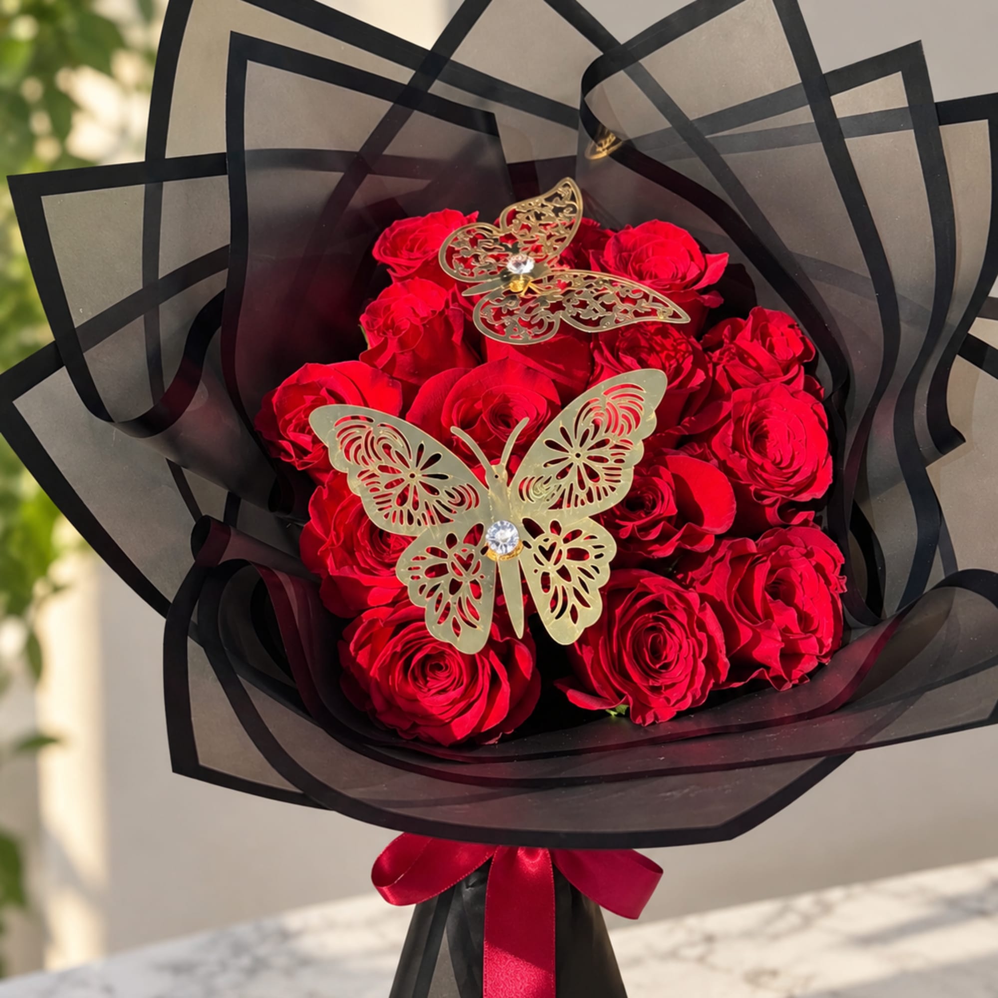 Bouquet of red roses wrapped in black paper with butterfly decorations