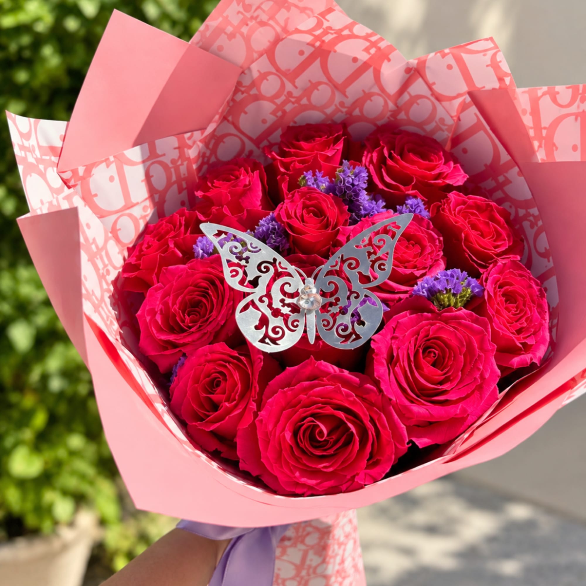 Bouquet of hot pink roses with purple filler flowers in pink wrapping
