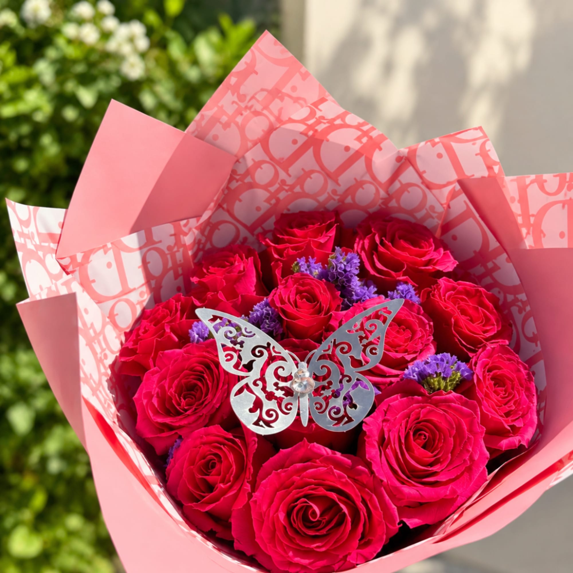 Bouquet of hot pink roses wrapped in pink paper with a butterfly pick