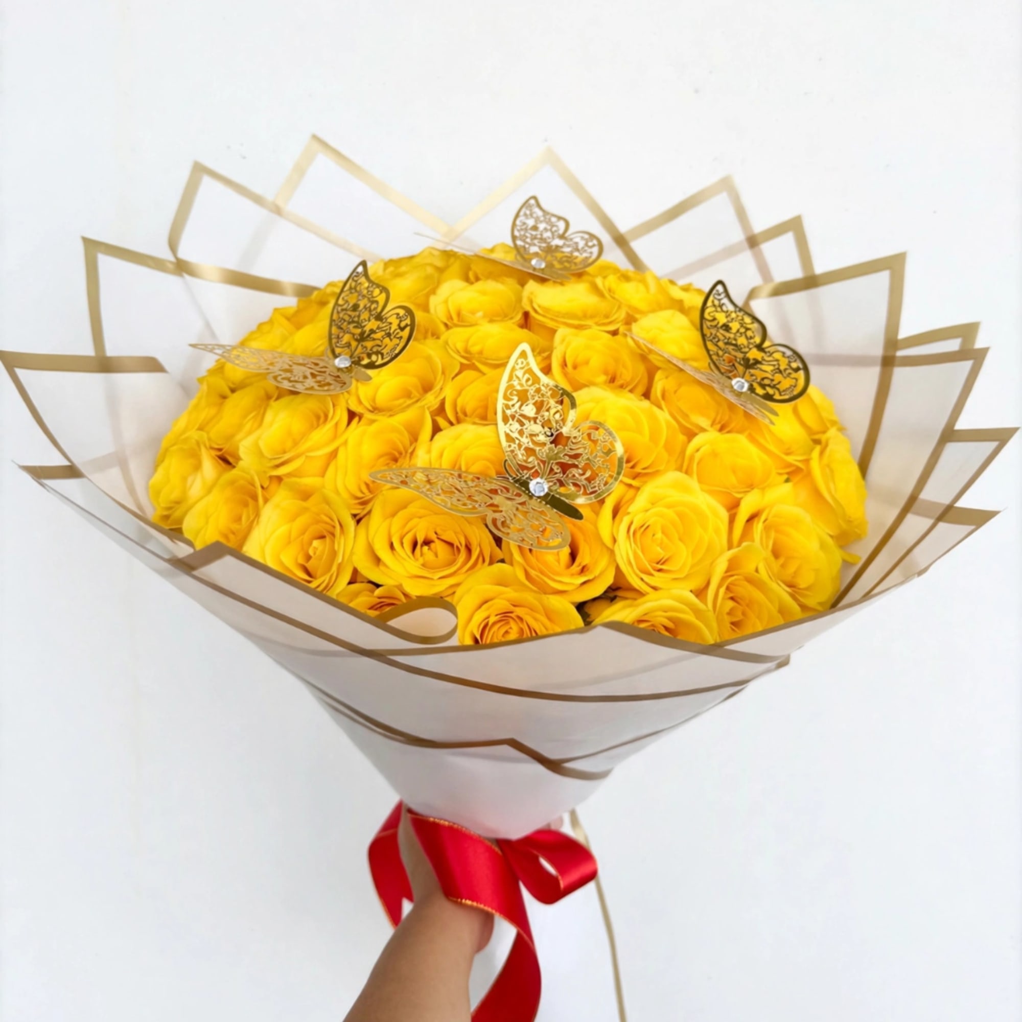 Bouquet of yellow roses wrapped in clear paper with gold butterfly picks