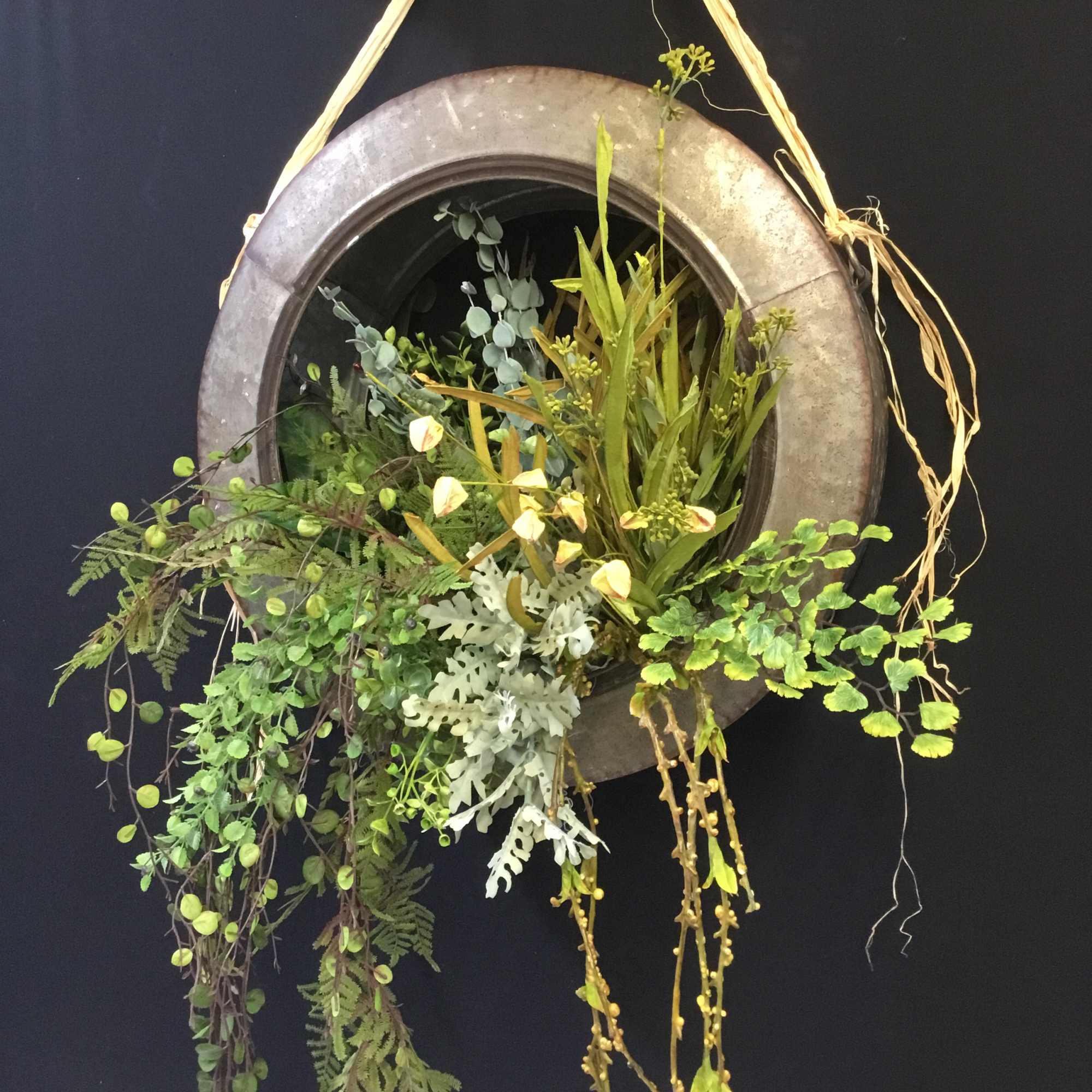 Hanging circular planter with trailing greenery and small pale flowers