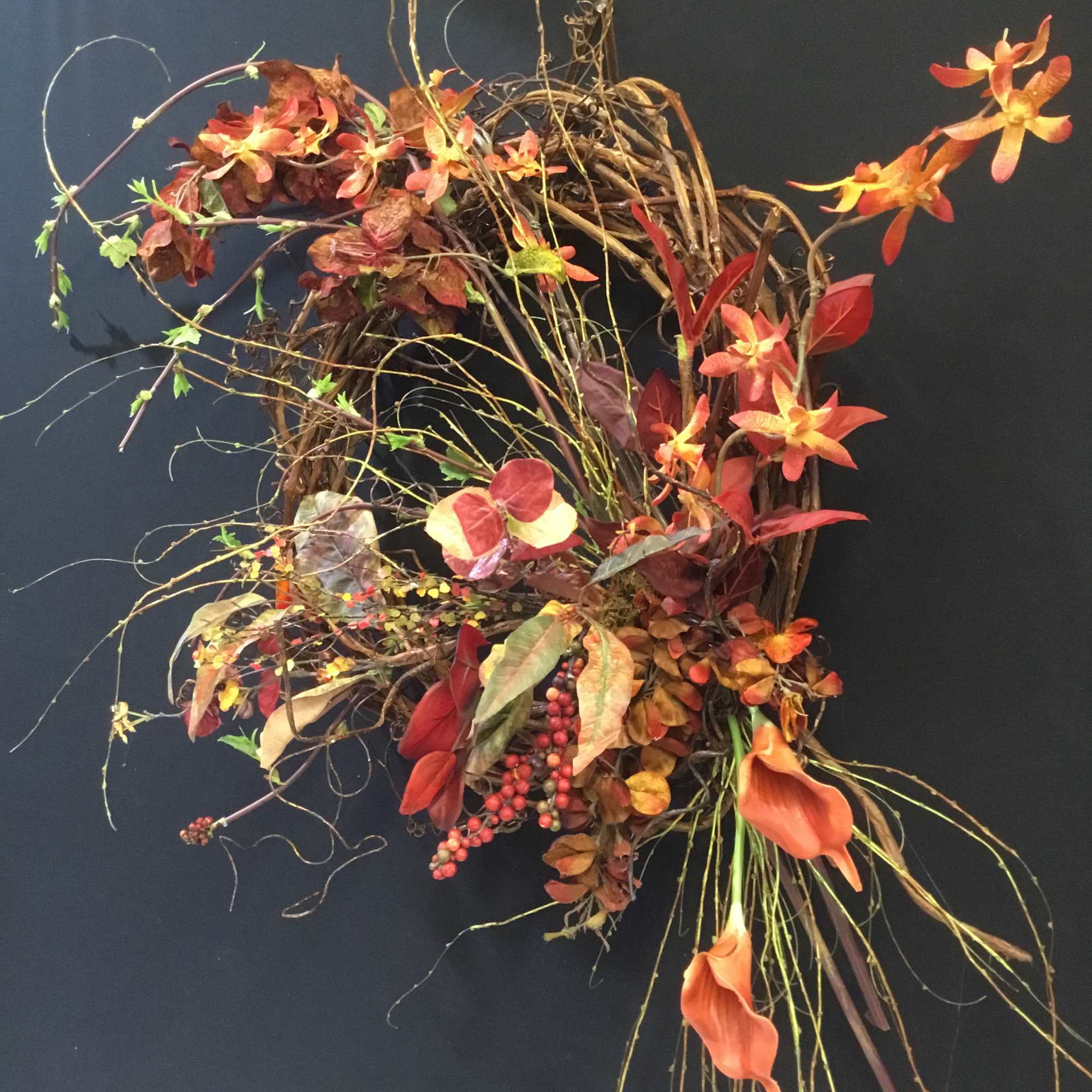 Abstract floral arrangement with orange flowers and twisting branches on a dark background