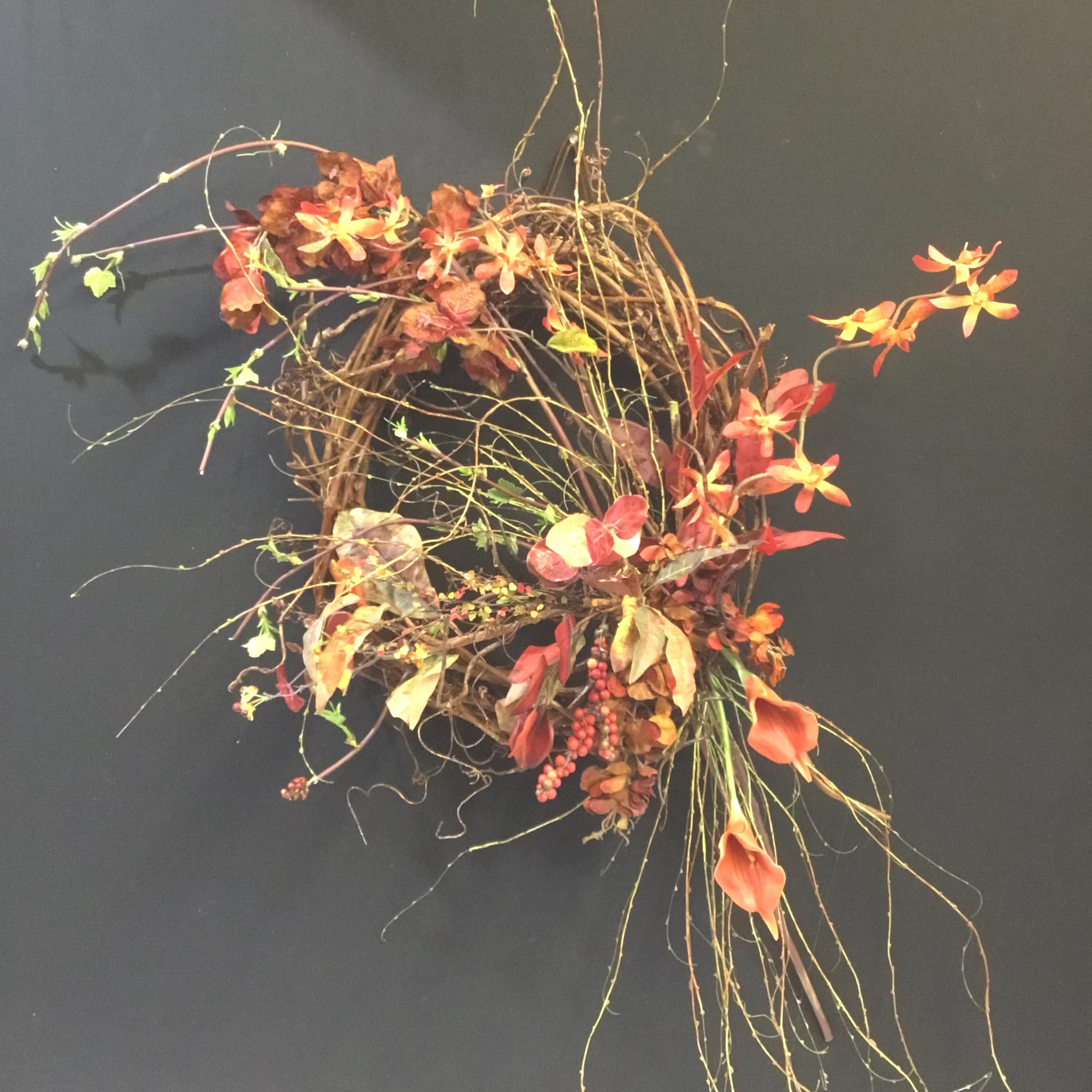 Abstract floral wreath with orange blooms and twisting vines on a dark background