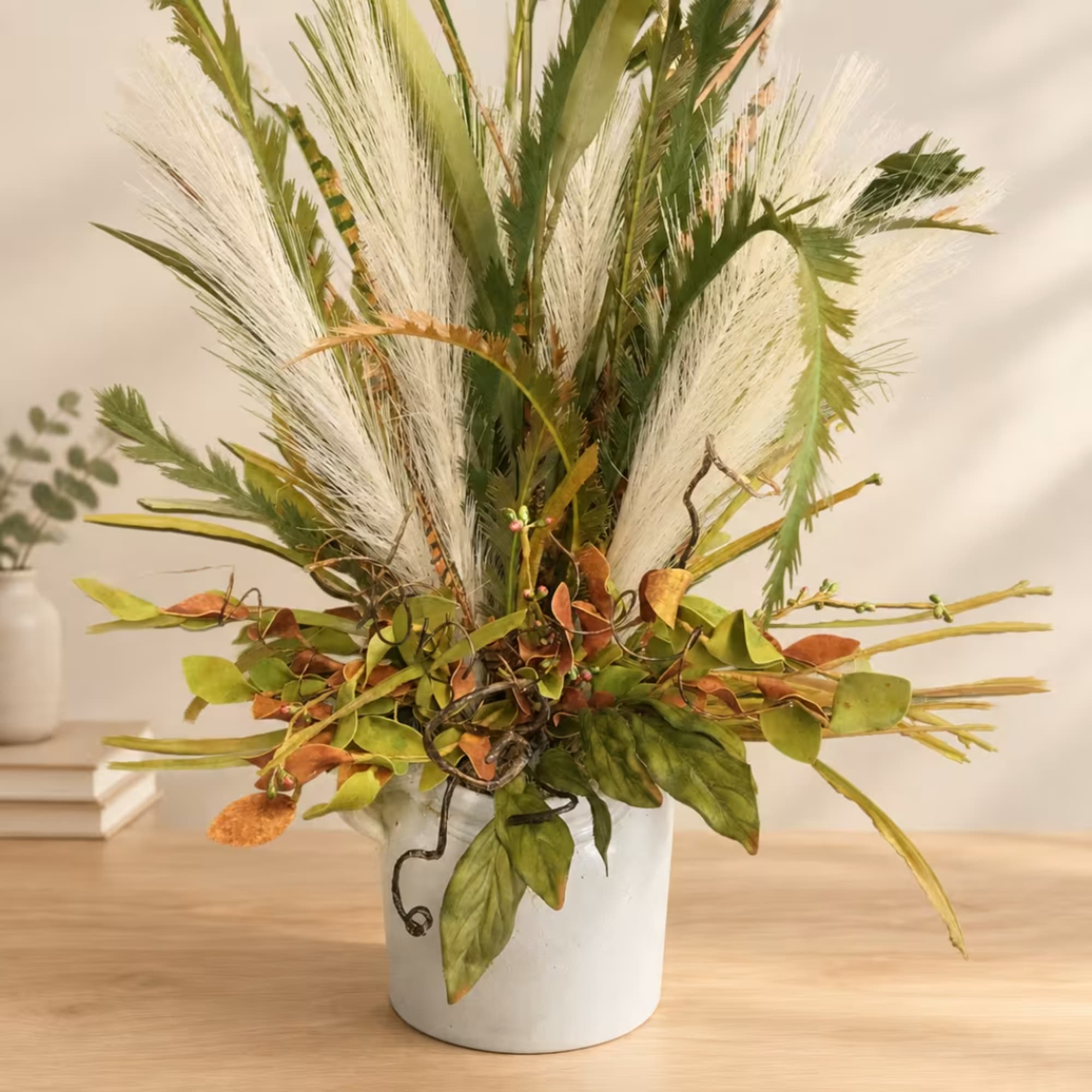 Tall arrangement of white feathery plumes and mixed greenery in a white vase