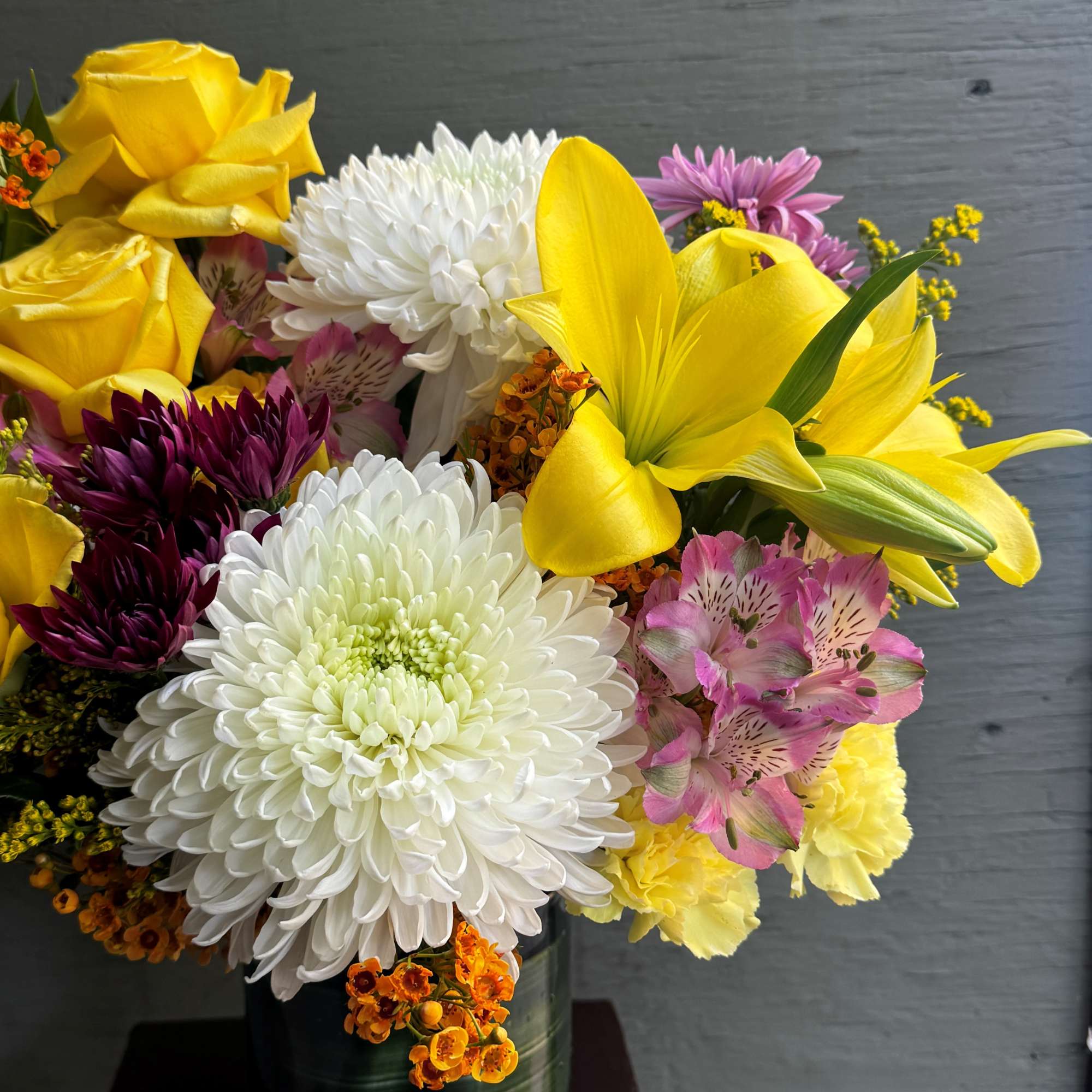 Bouquet of yellow roses, white chrysanthemums, and pink alstroemeria in a glass vase