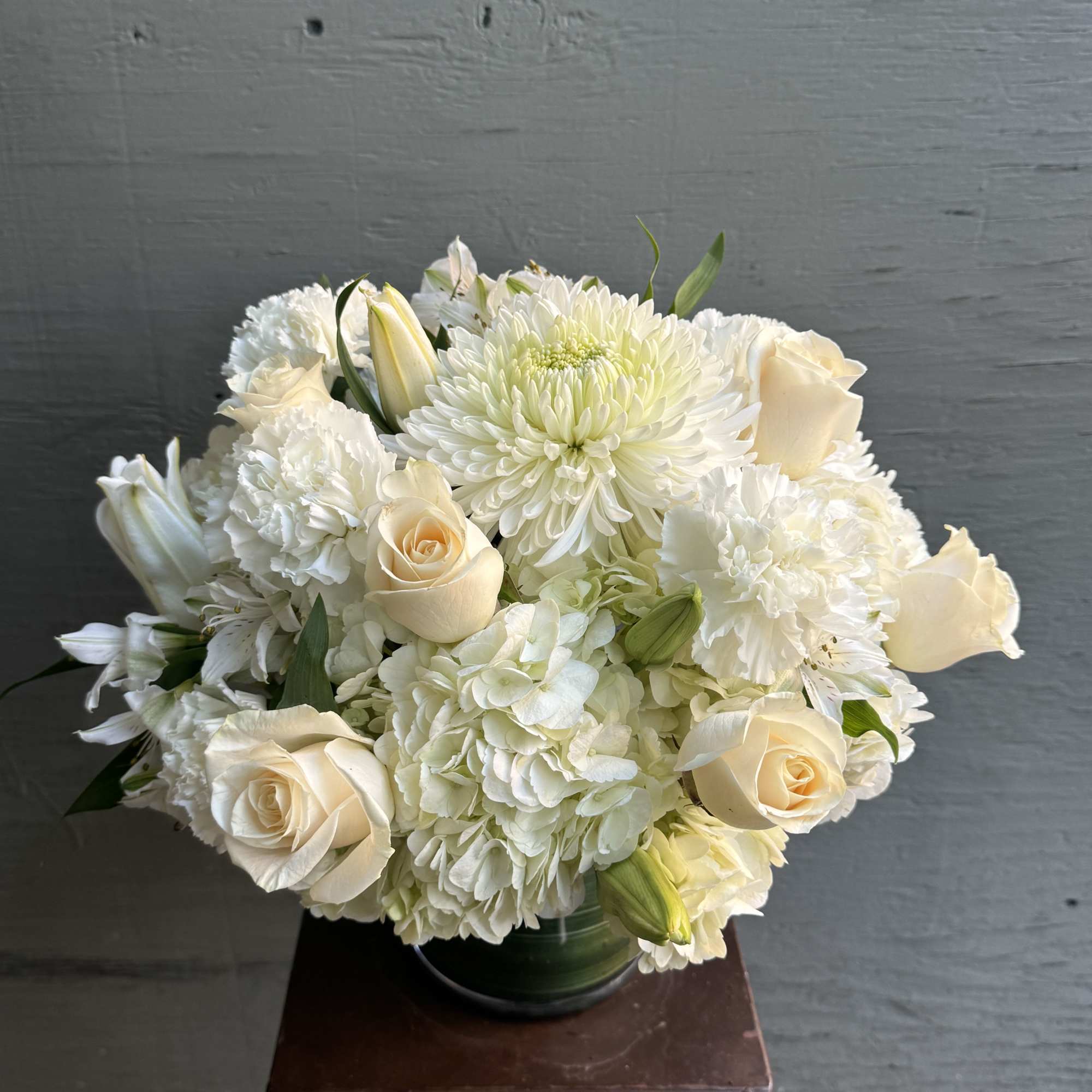 White floral bouquet with cream roses and chrysanthemums in a glass vase