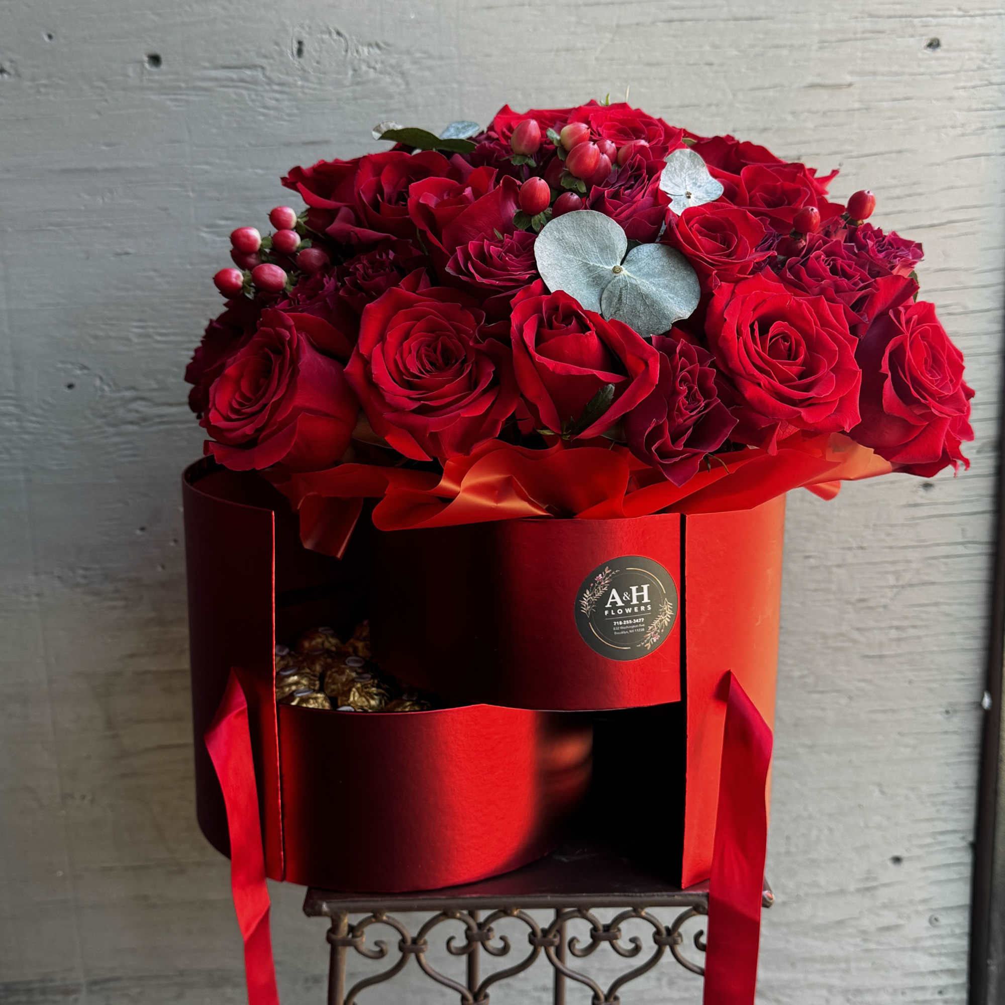 Red rose arrangement in a red hat box with ribbon