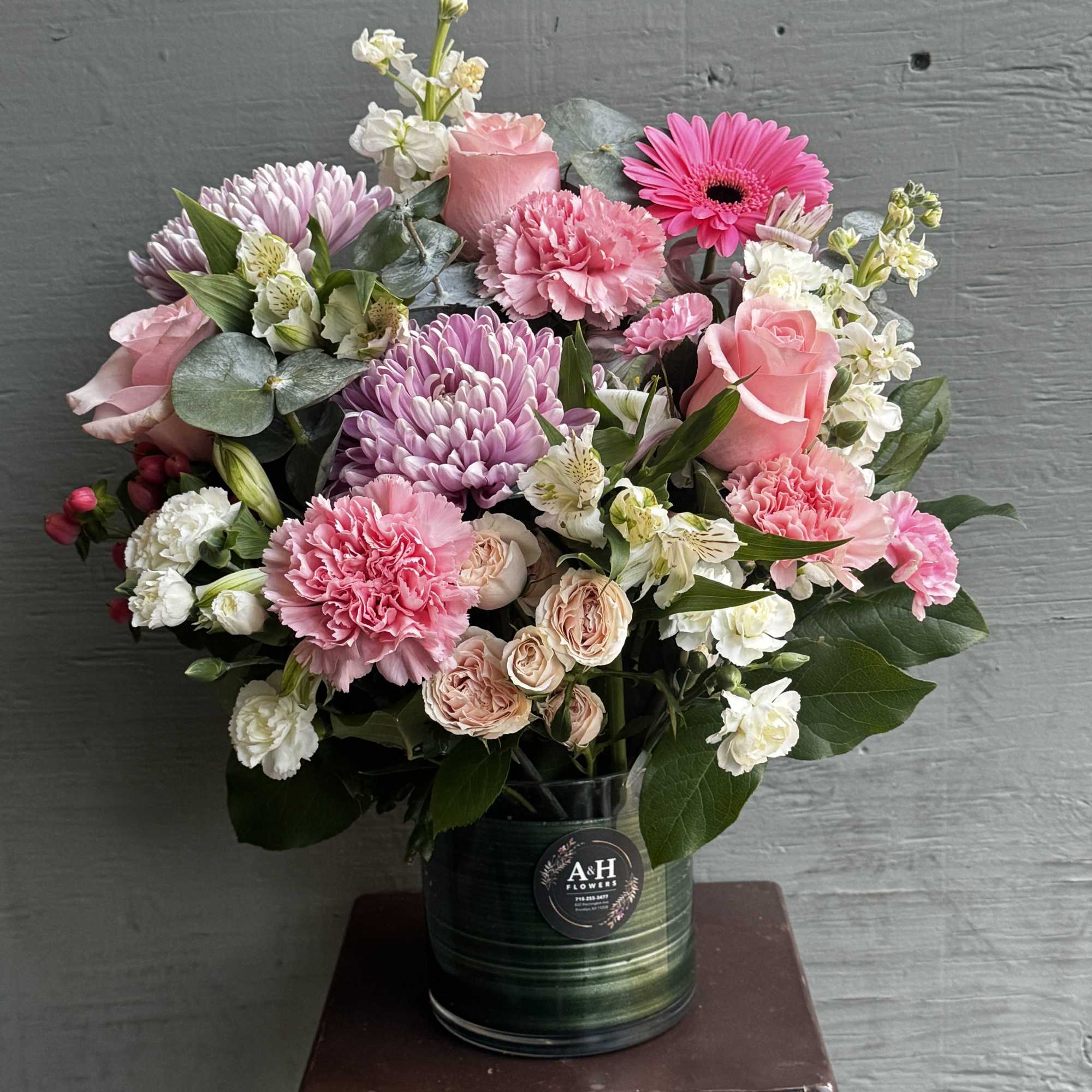Pink and white mixed flower arrangement in a dark vase
