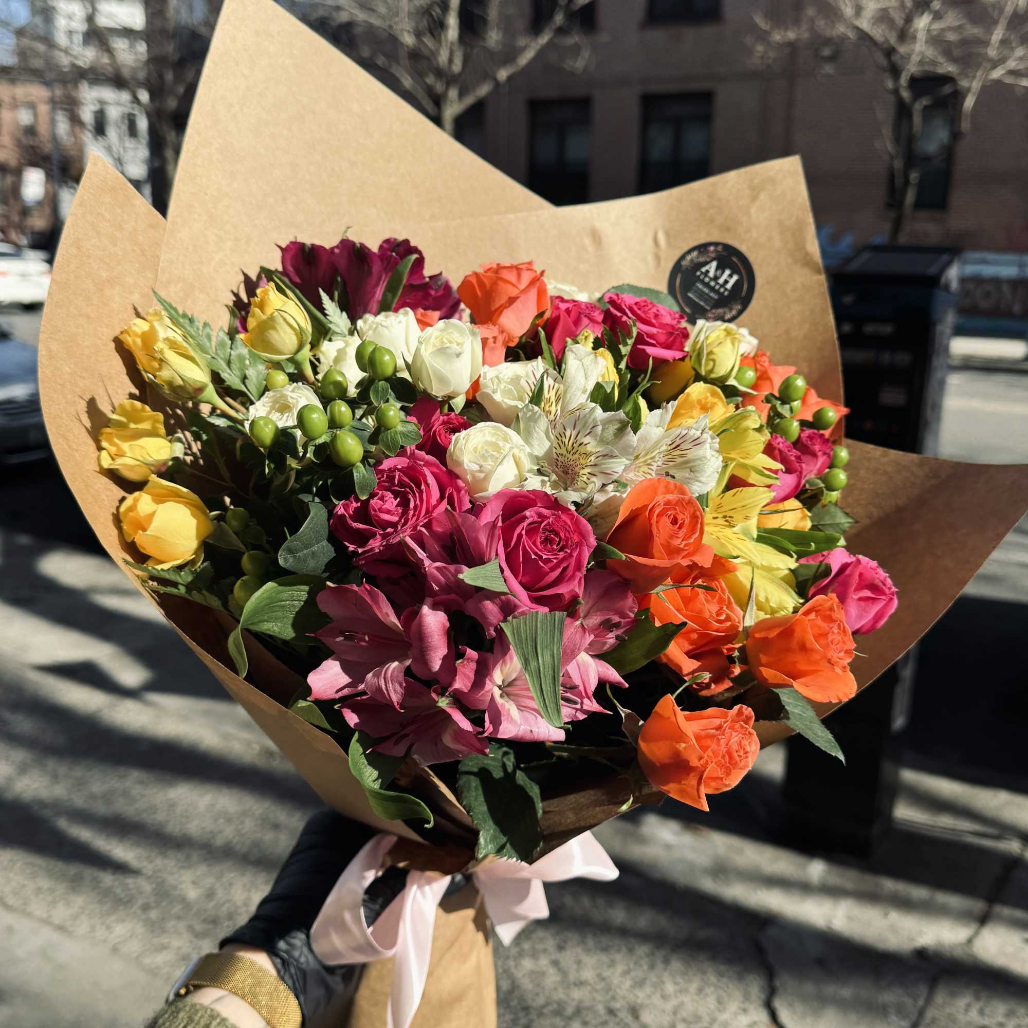 Mixed bouquet of colorful roses and alstroemeria wrapped in kraft paper