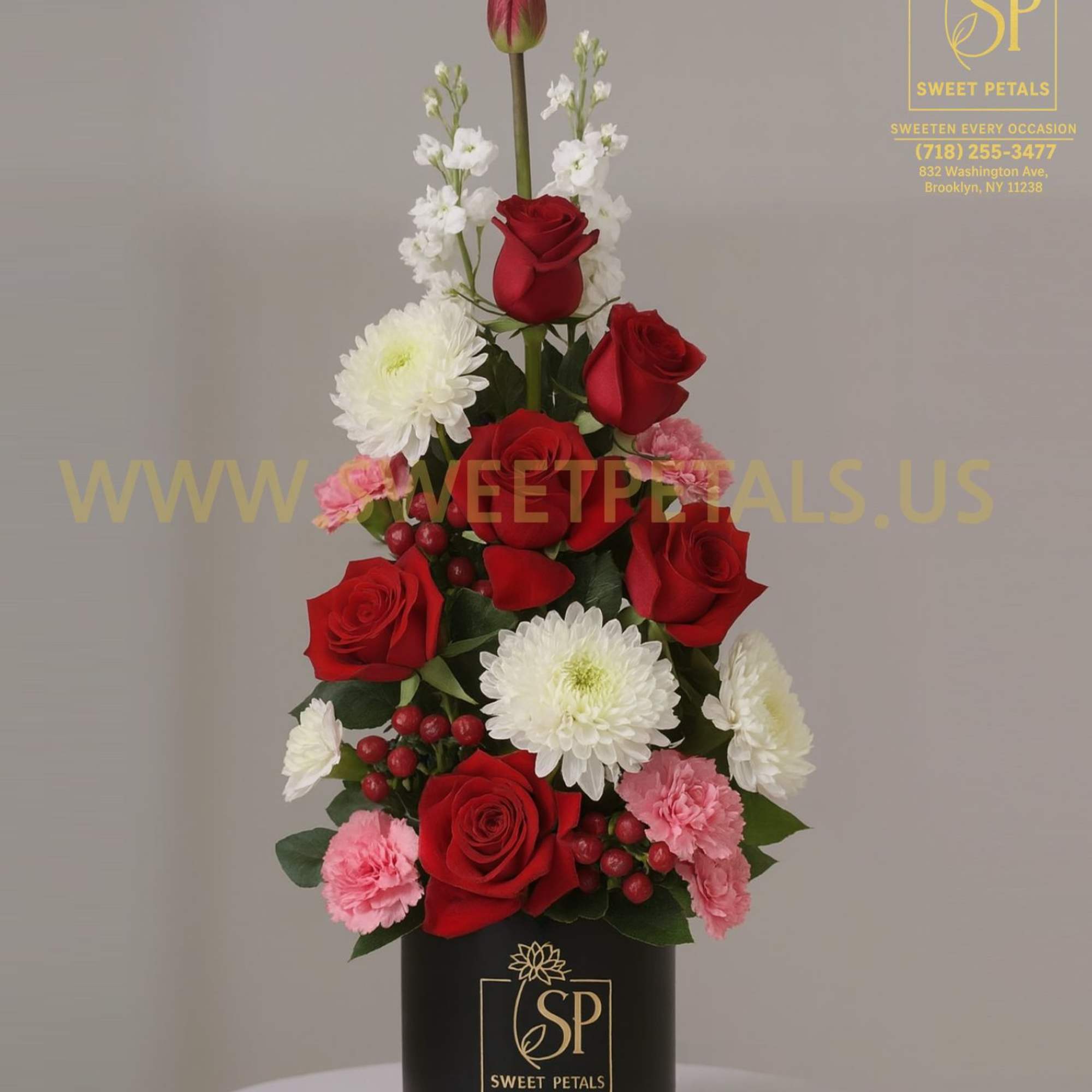 Red roses and white flowers arranged in a tall black box