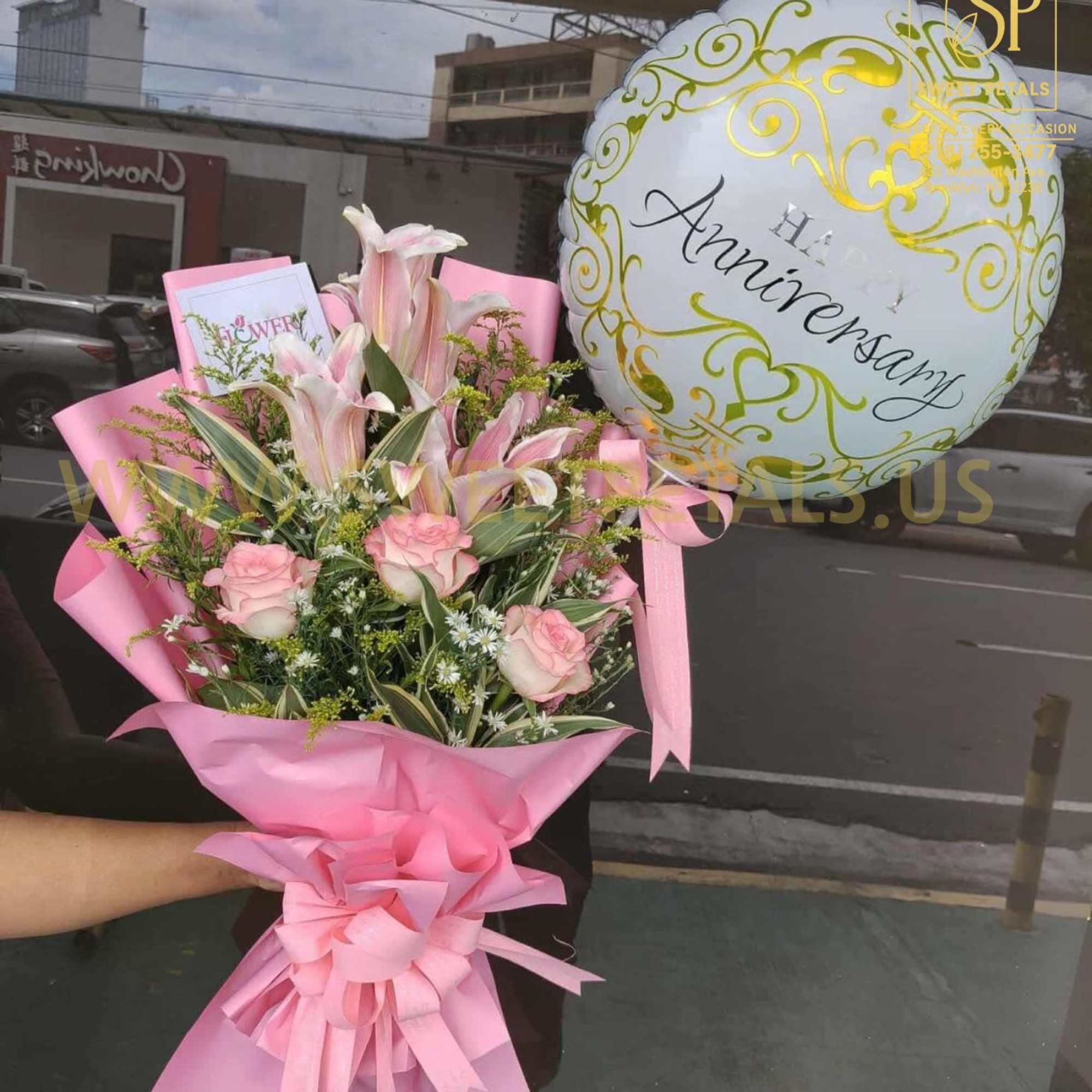 Pink bouquet with roses and lilies beside a white anniversary balloon
