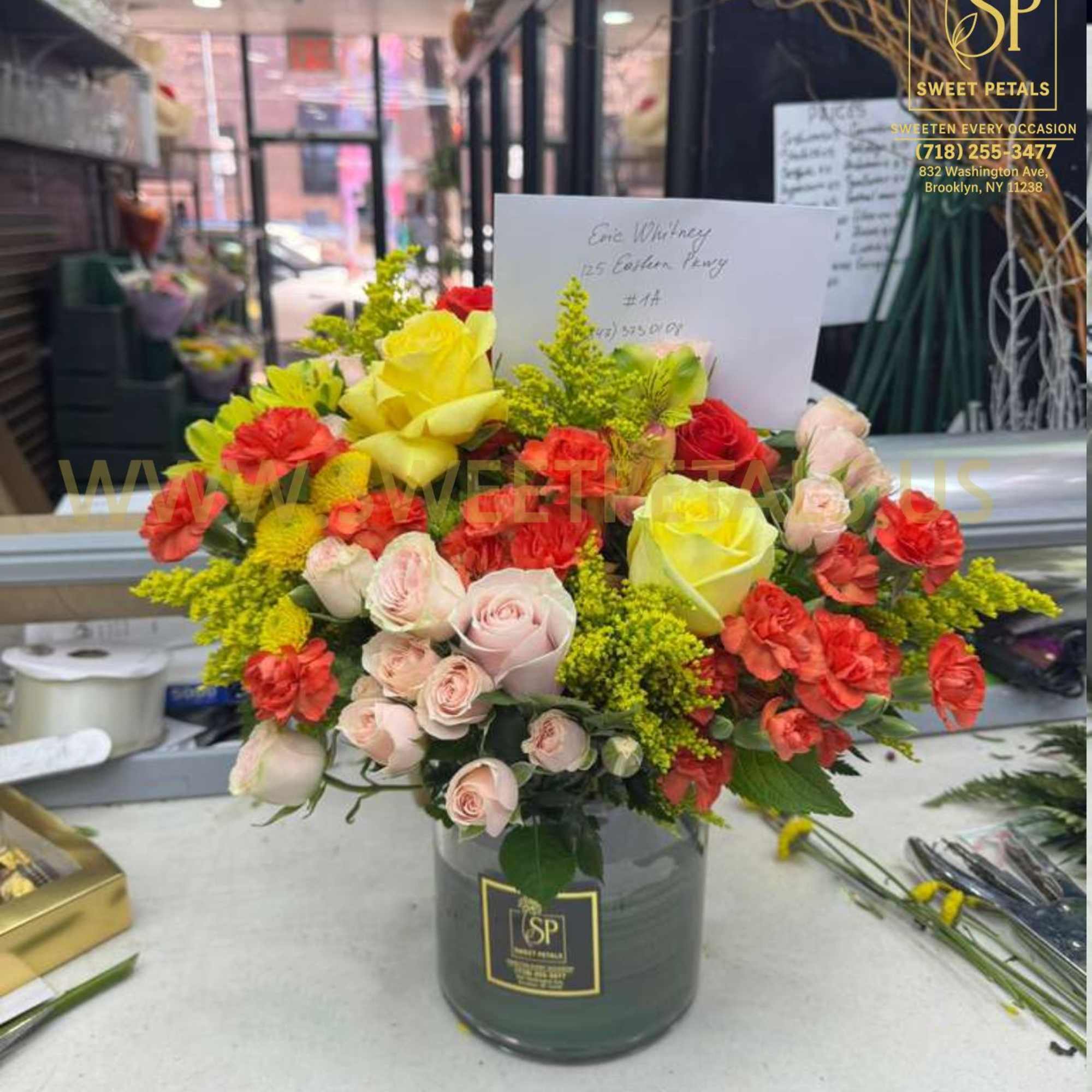 Mixed bouquet of yellow, pink, and red roses in a glass vase