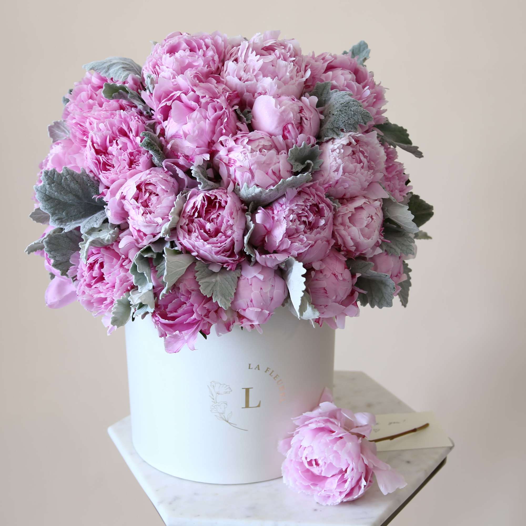 Pink peony bouquet in a white hatbox with a single bloom beside it