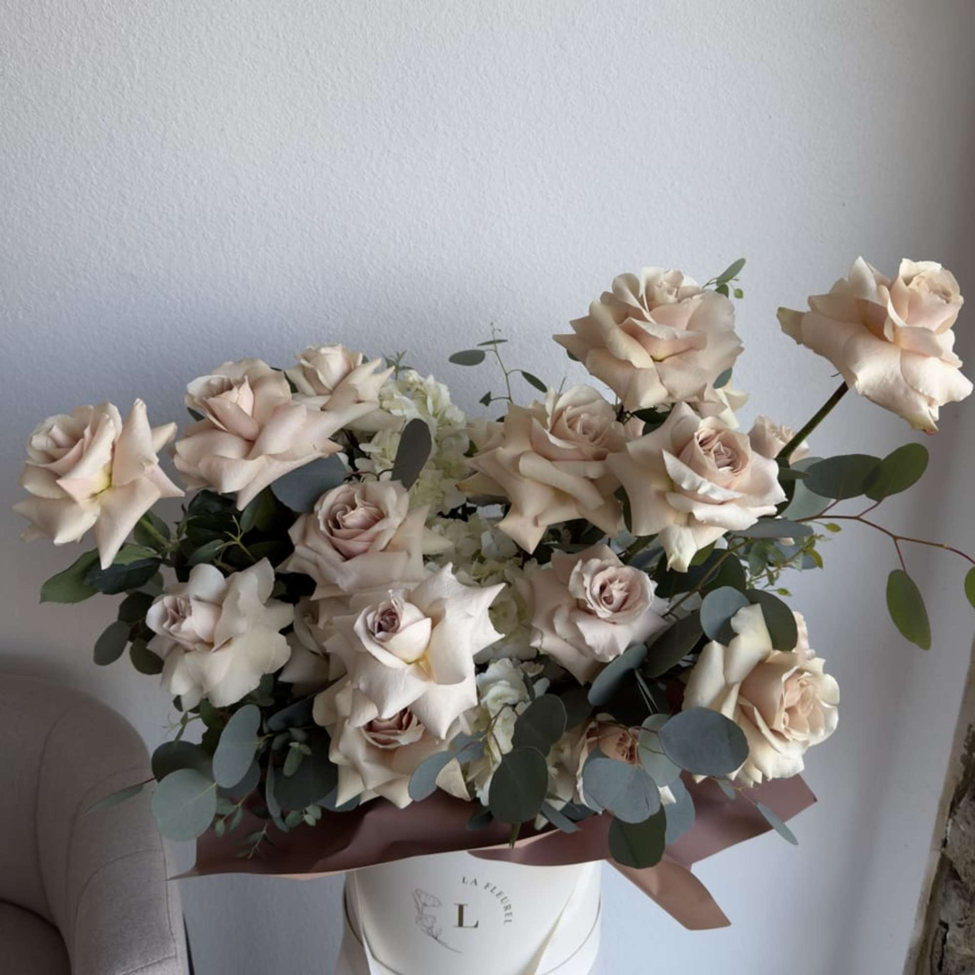 This beautiful arrangement is filled with beige color roses and greens to, photo 2 of 3