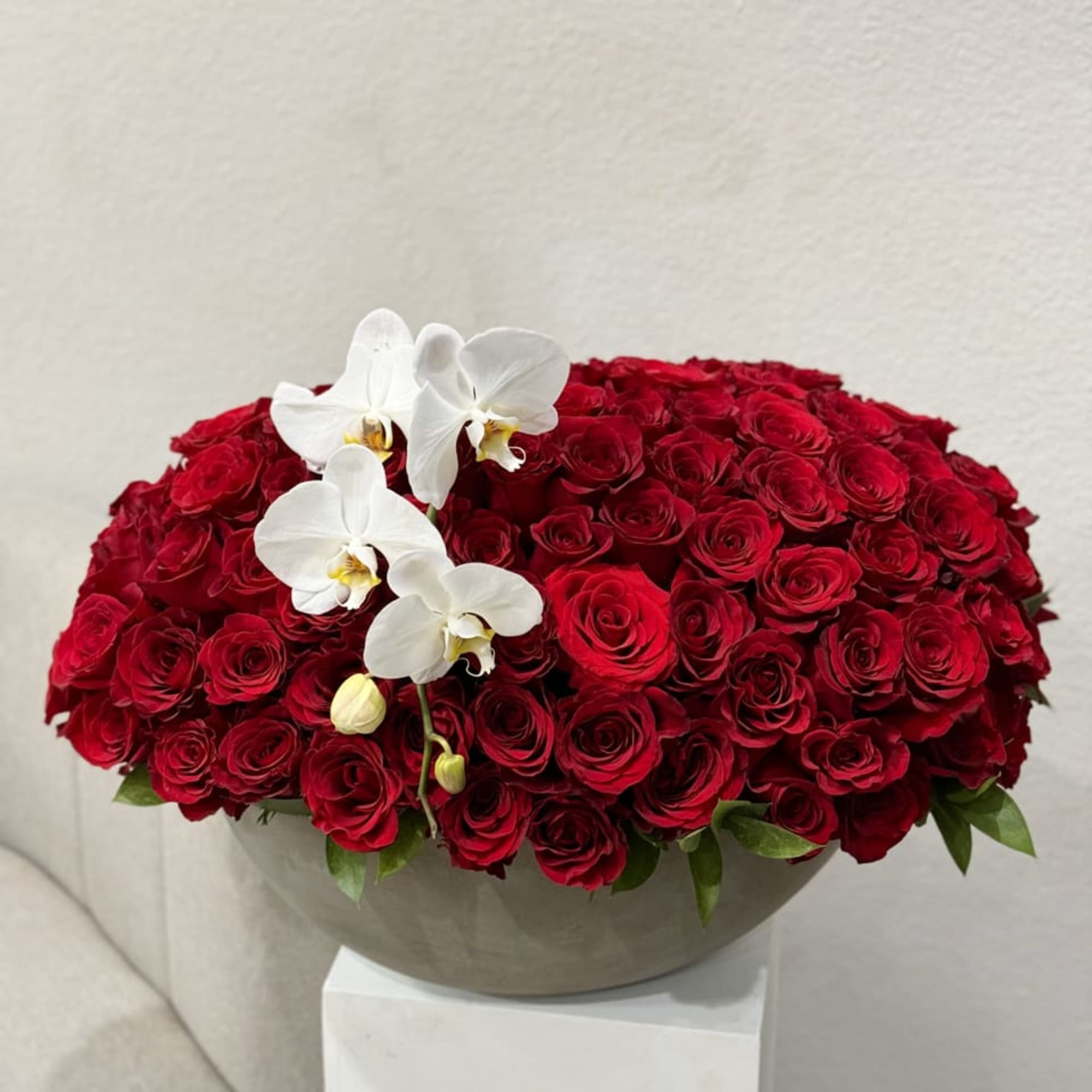An opulent bouquet of 100 radiant red roses, beautifully arranged in a