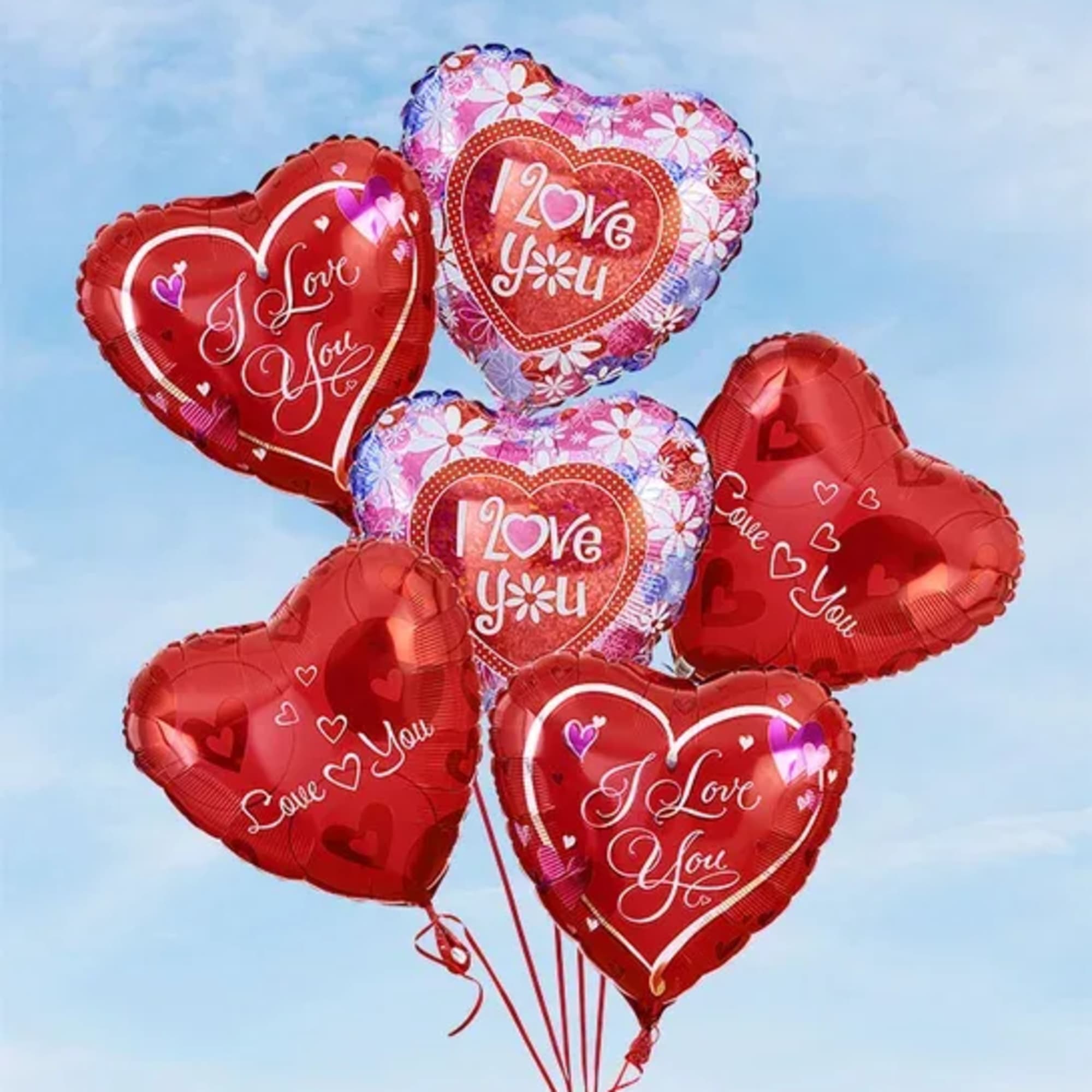 Cluster of heart-shaped red and pink balloons with love messages