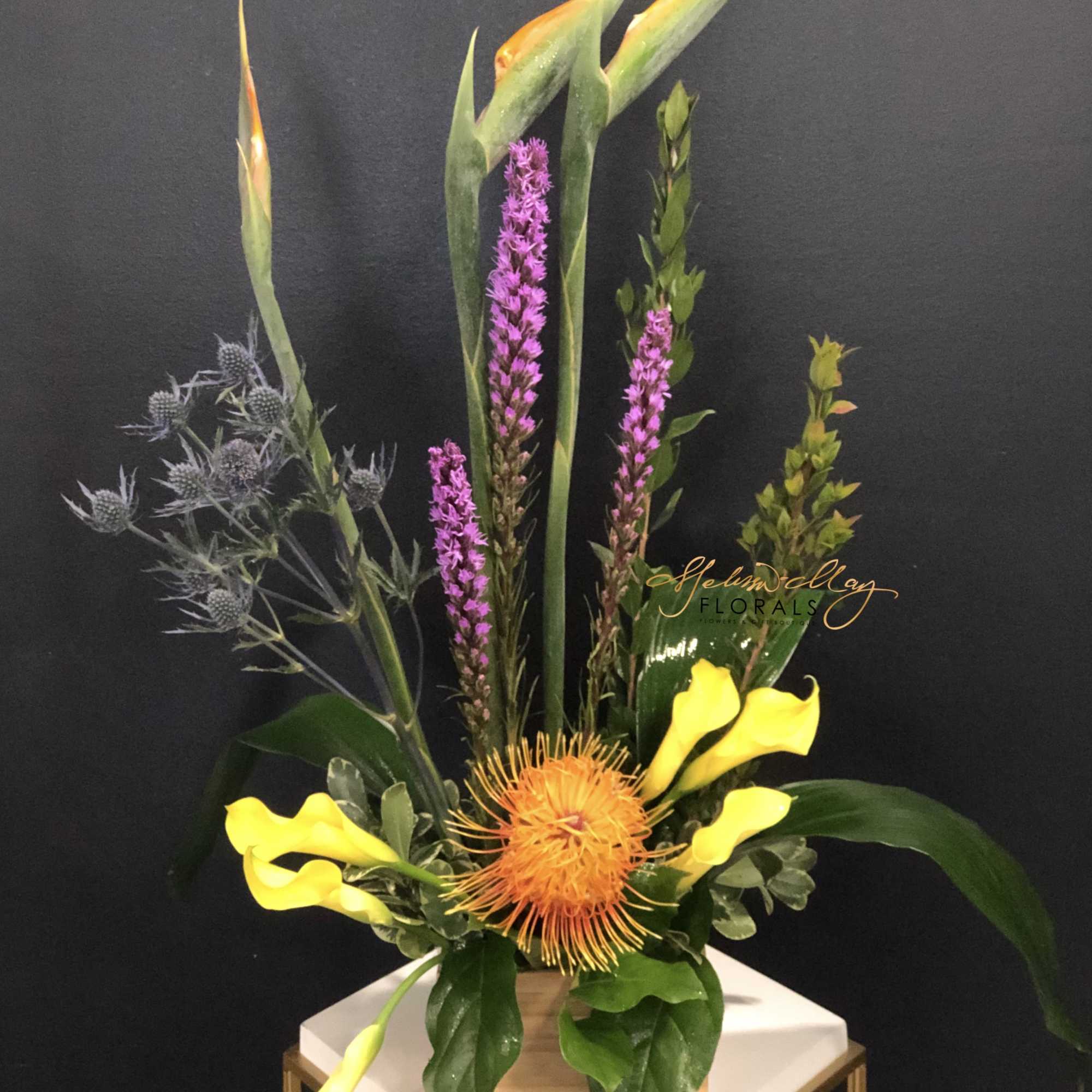 This bold mix of exotic tropical elements, greenery and flowers soars upwards