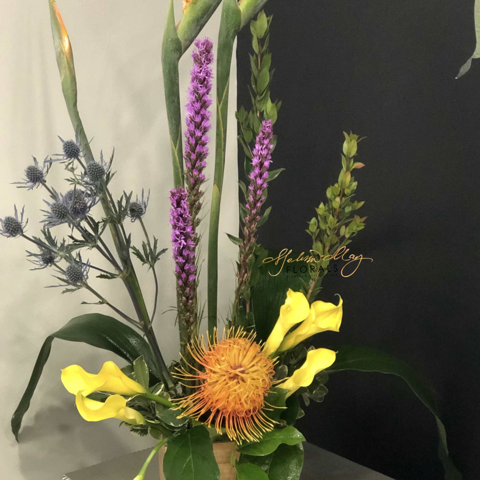 This bold mix of exotic tropical elements, greenery and flowers soars upwards