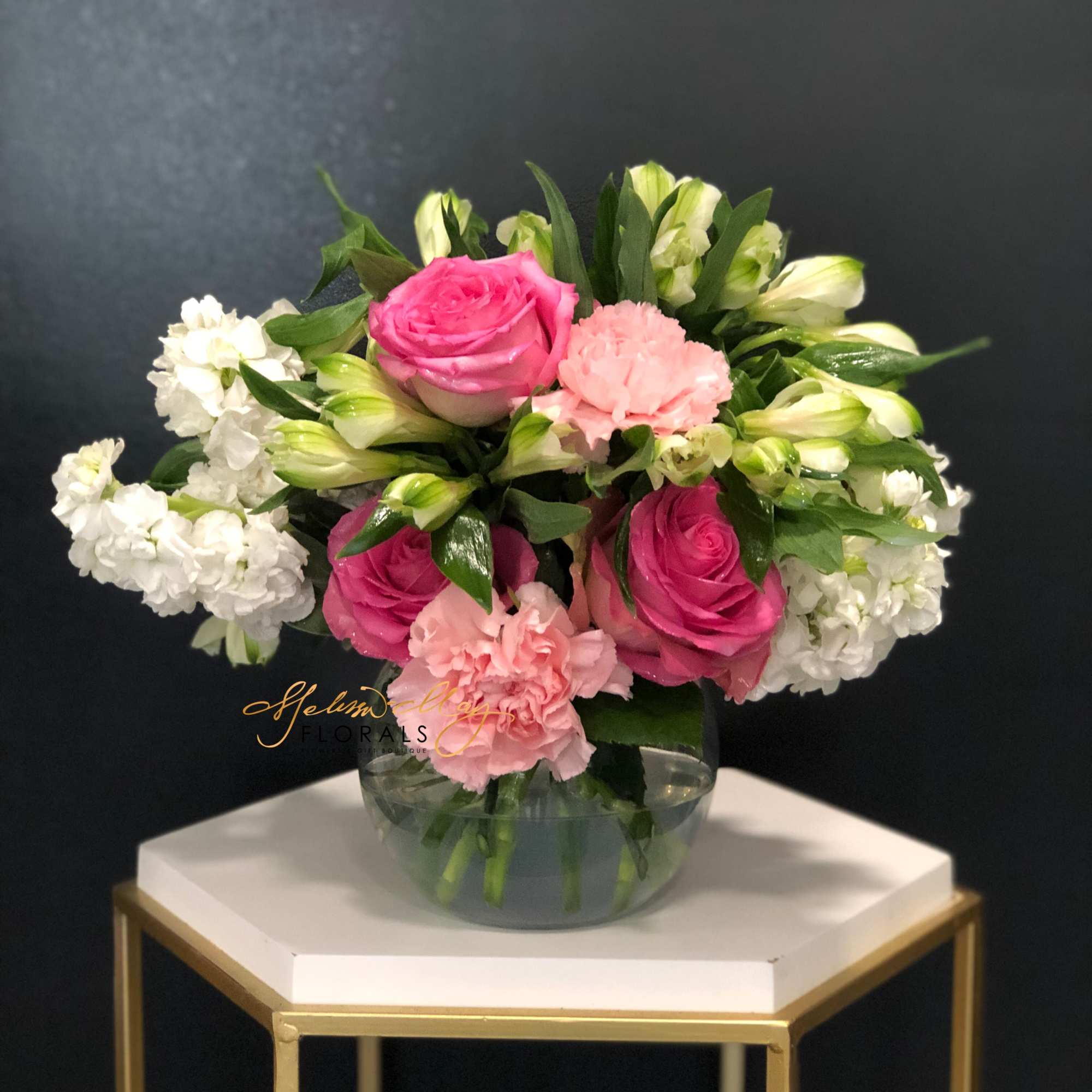 This soft display of pink carnations, alstromeria, and purple roses with a