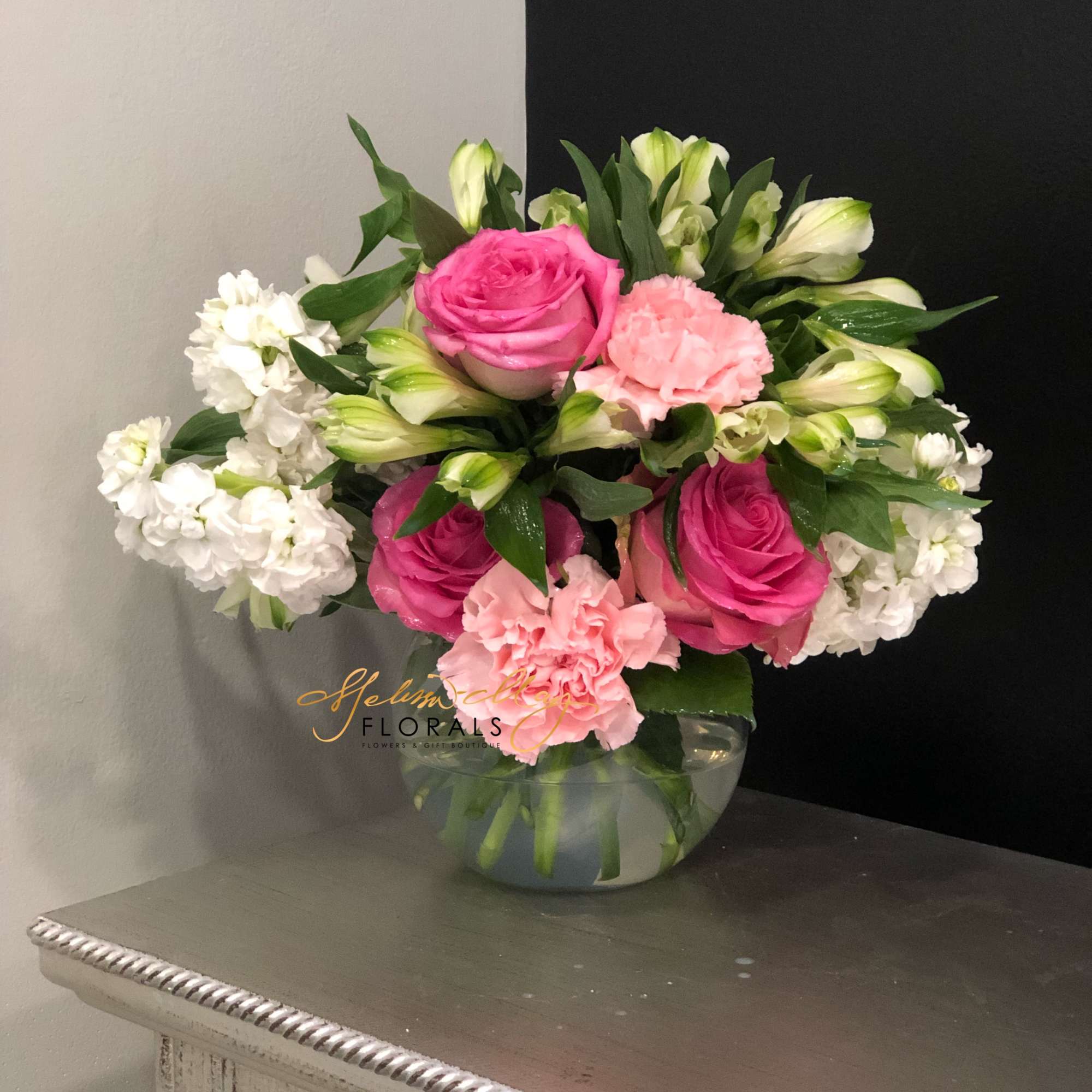 This soft display of pink carnations, alstromeria, and purple roses with a