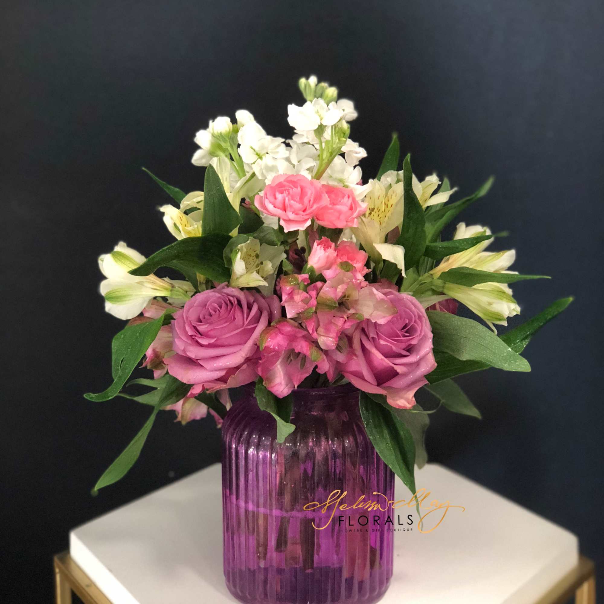 A small arrangement with lavender roses, pink carnations, and white alstroemerias. All
