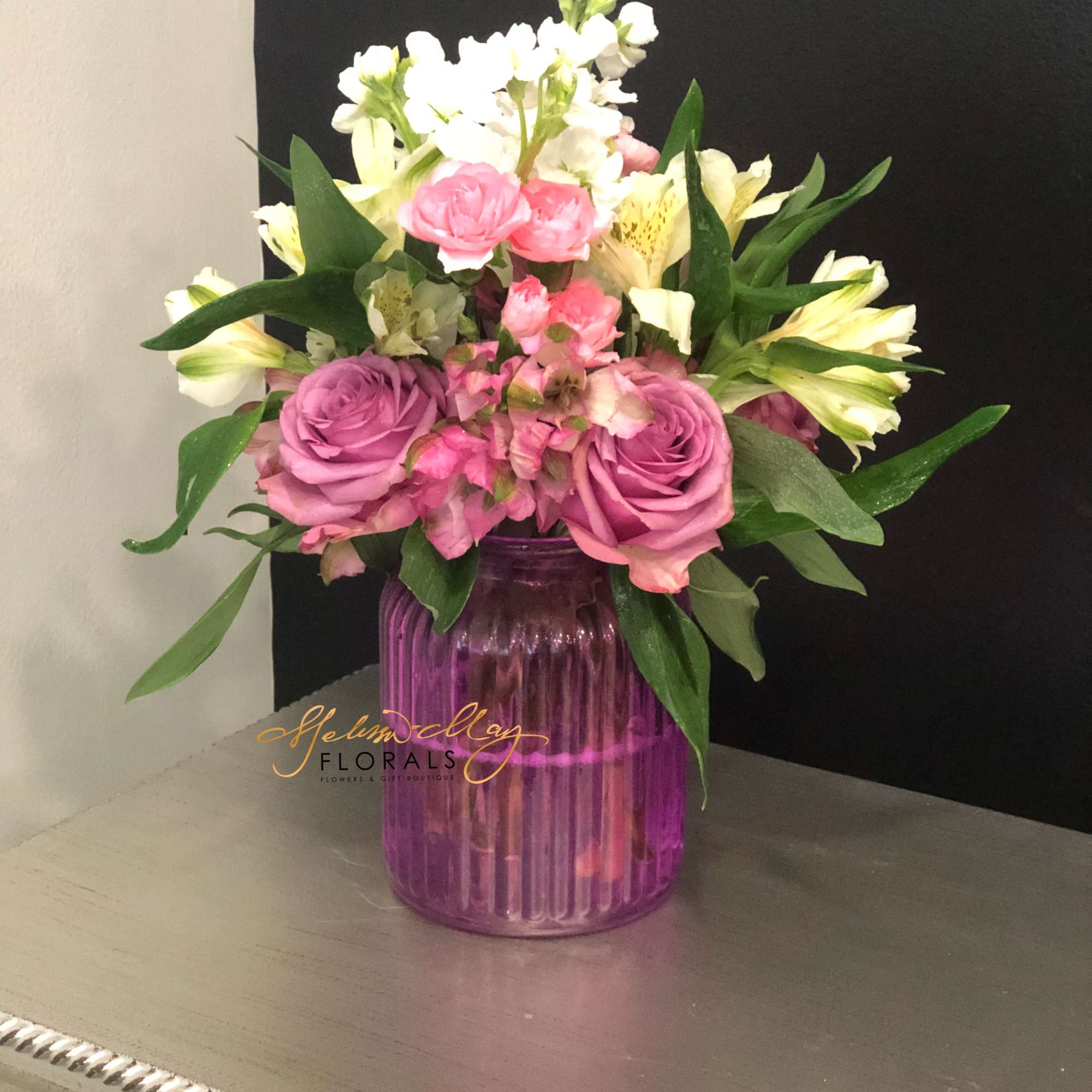 A small arrangement with lavender roses, pink carnations, and white alstroemerias. All