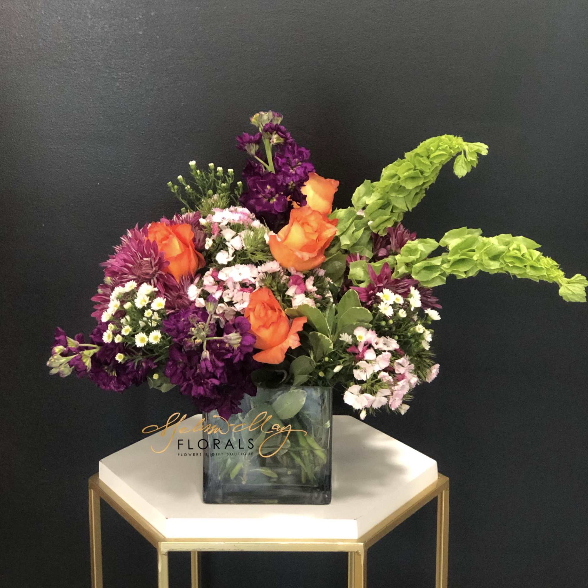 This magnificent arrangement with deep purples and bright oranges will illuminate the