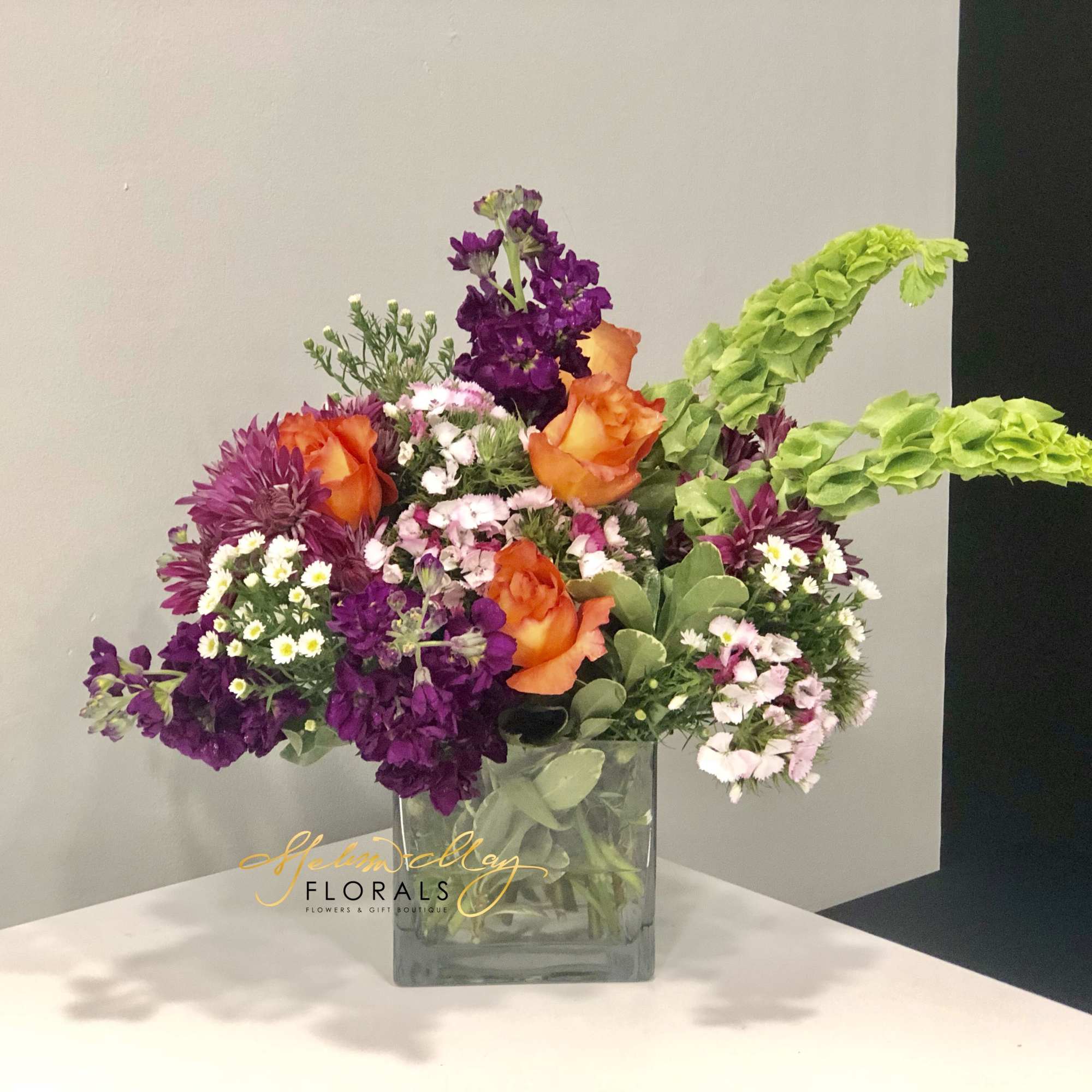 This magnificent arrangement with deep purples and bright oranges will illuminate the
