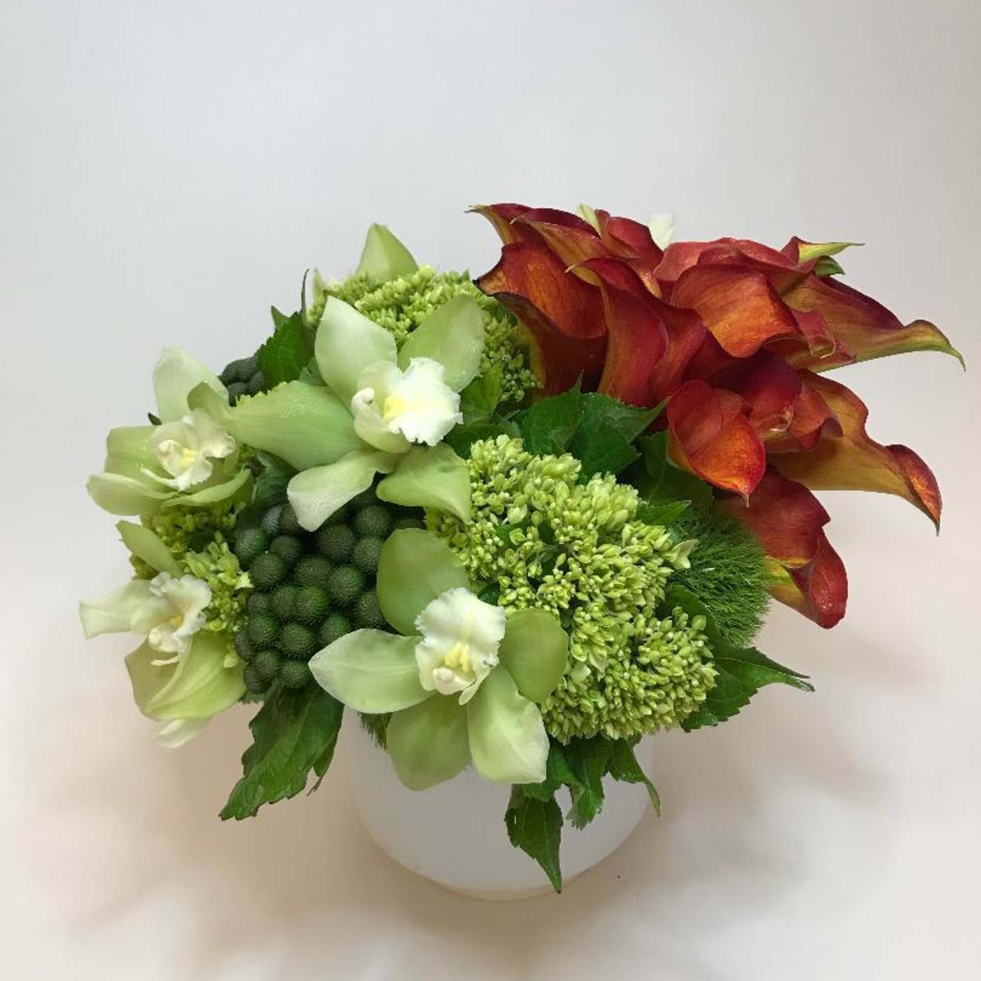 vibrant callas surrounded by multiple textural elements of orchids, green hydrangea, and