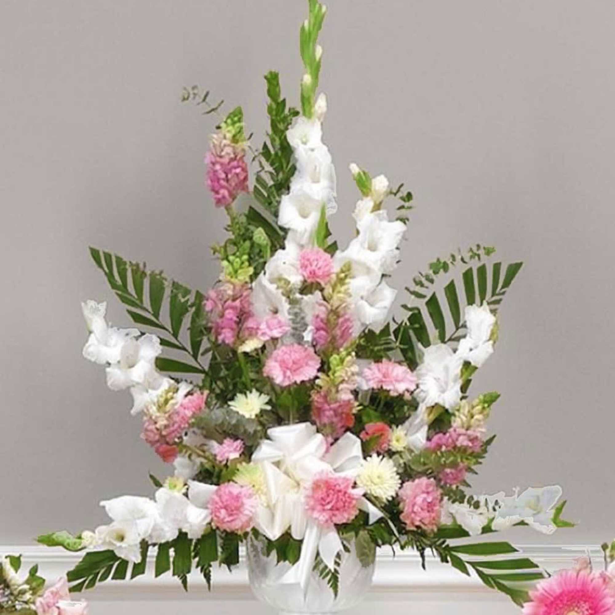 White Gladiolus cascade from a bouquet of Pink Snapdragons, Carnations and designer