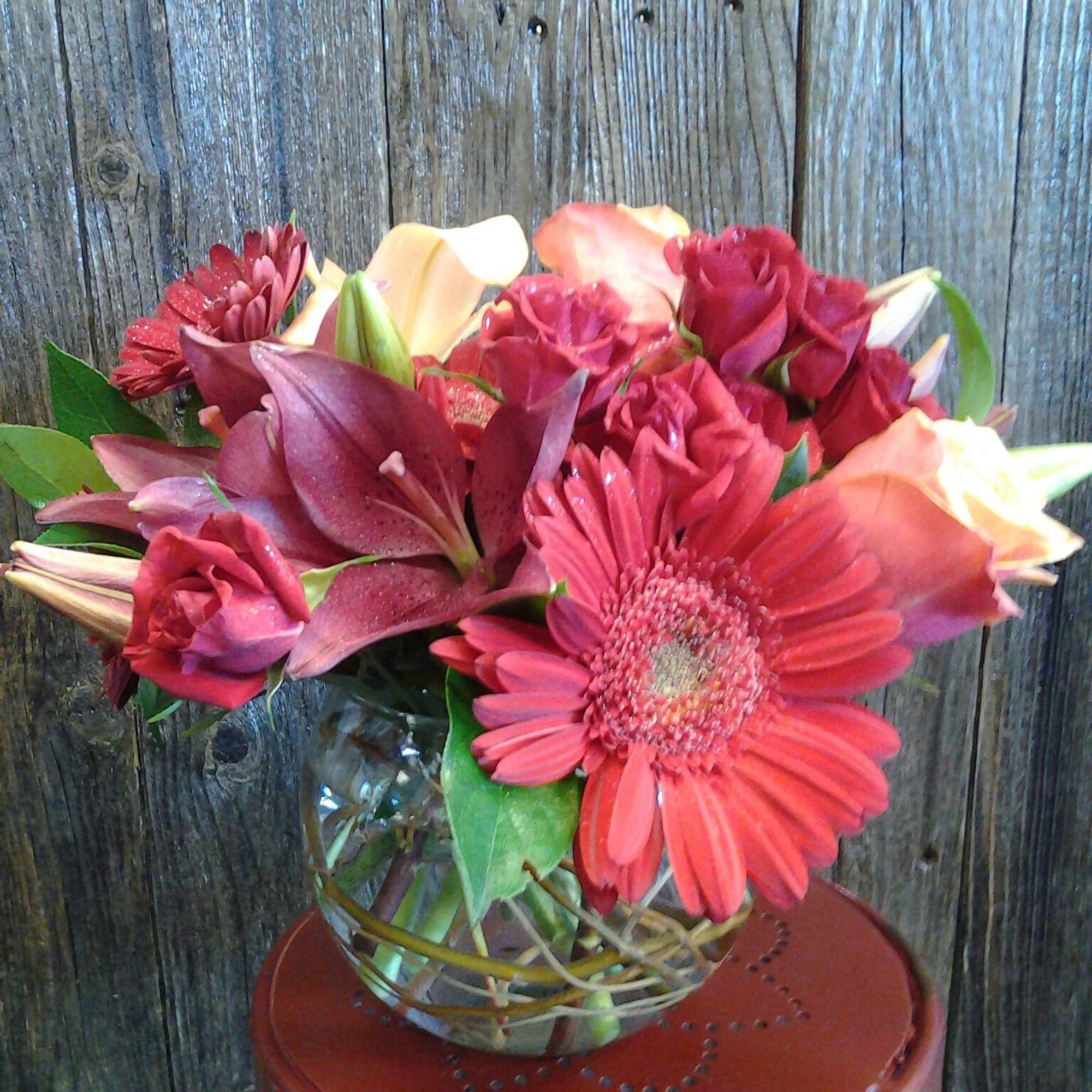 With a mixture of roses, asters, other flowers along with some bling