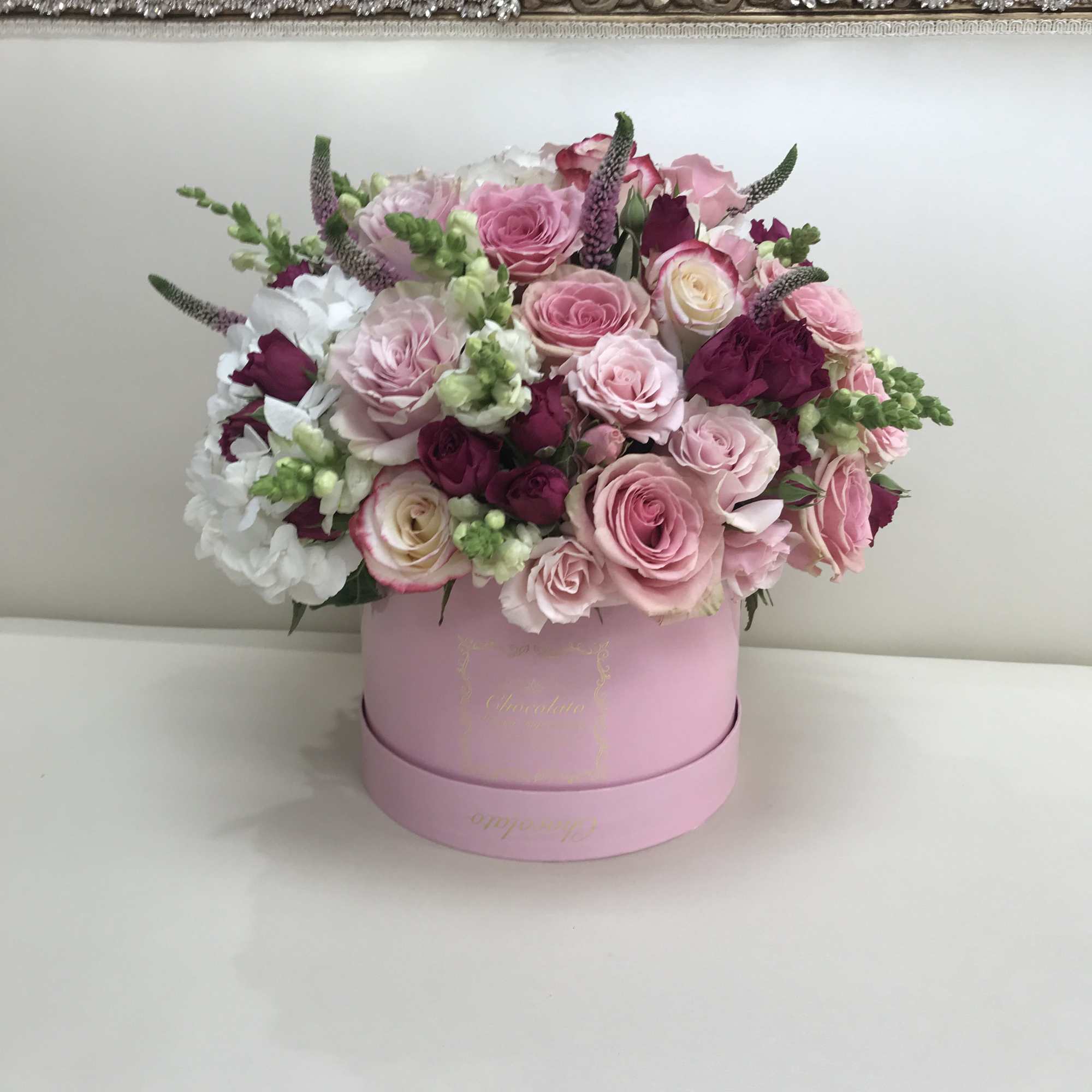 This Chocolato arrangement is made with Pink and Purple Roses, White Snapdragons