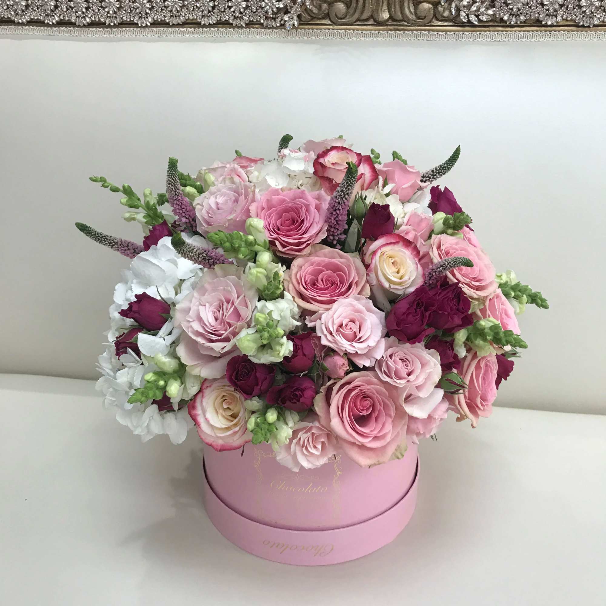 This Chocolato arrangement is made with Pink and Purple Roses, White Snapdragons