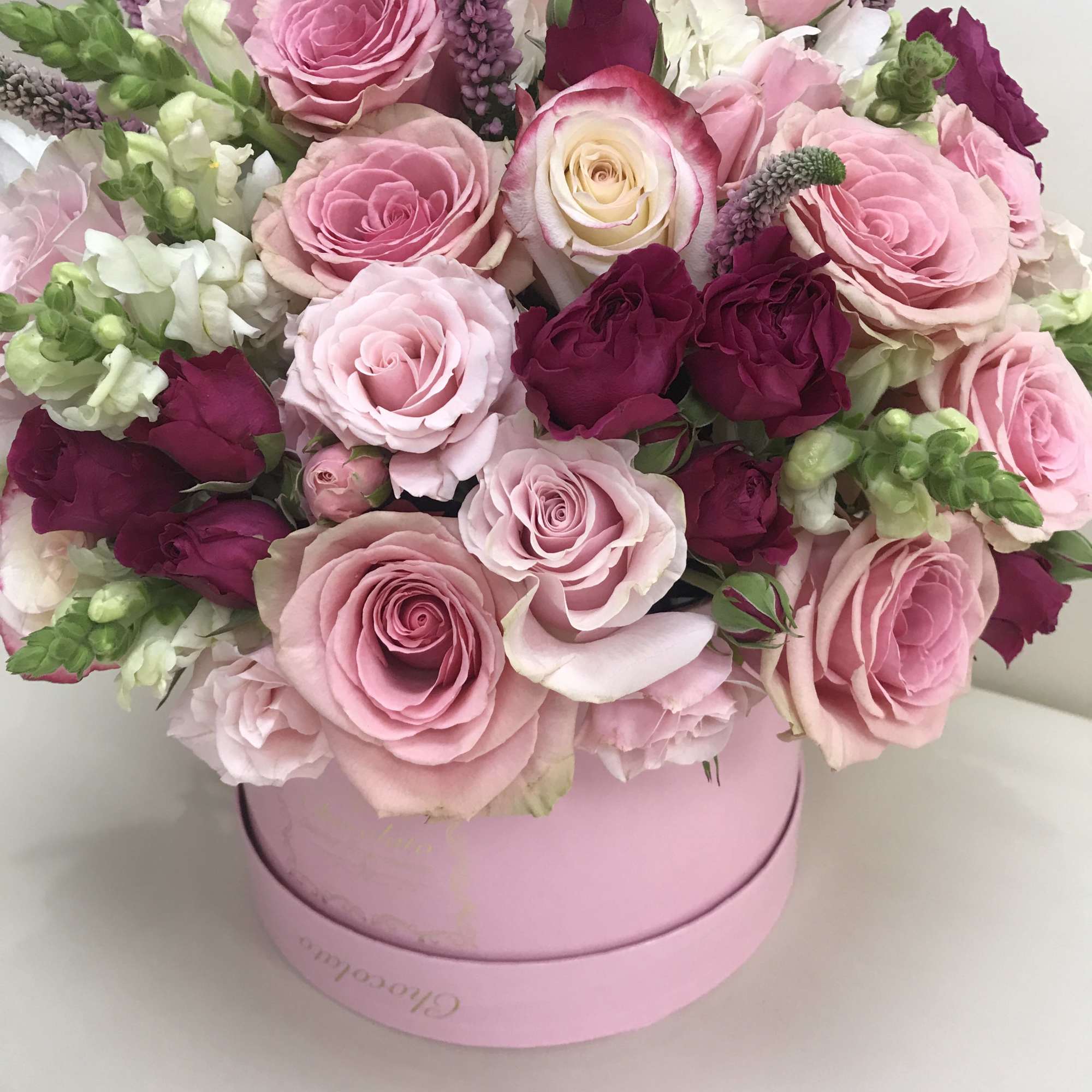 This Chocolato arrangement is made with Pink and Purple Roses, White Snapdragons