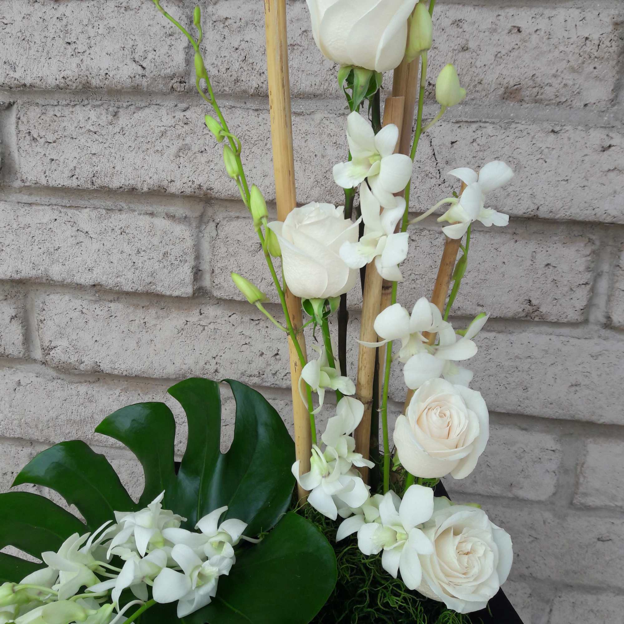Orchids and roses arranged beautifully with bamboo. This tropical style is sure