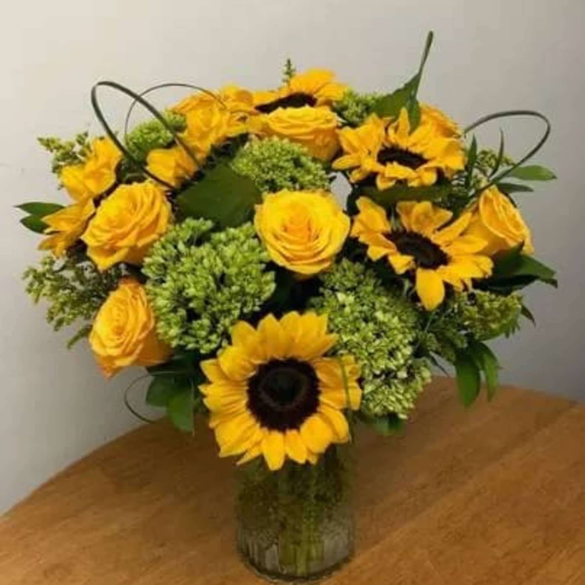 Vibrant Sunflowers, bright yellow roses, fluffy green hydrangea and more are artfully