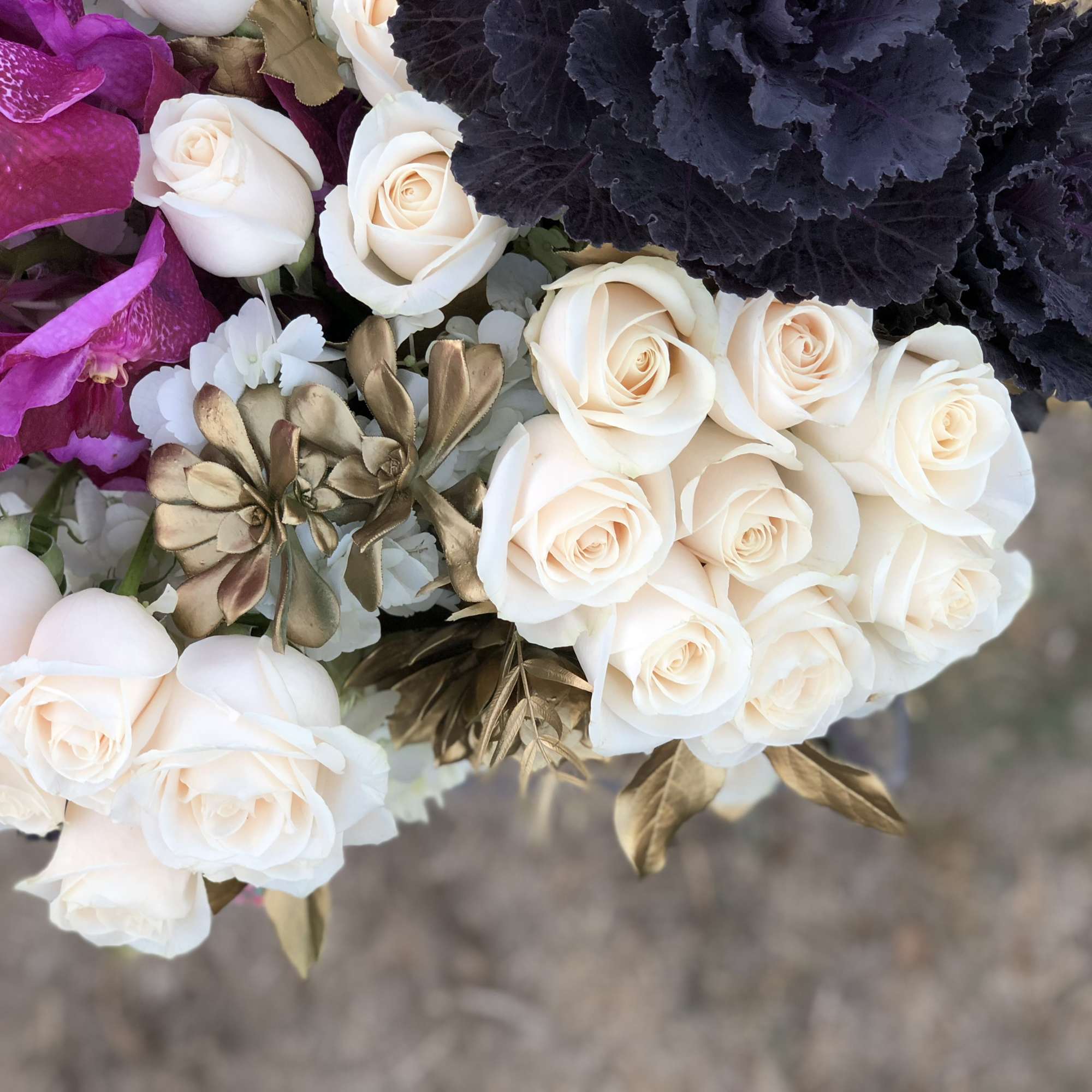 Unique arrangement with winter color flowers, cream roses, cream hydrangeas, orchids, and